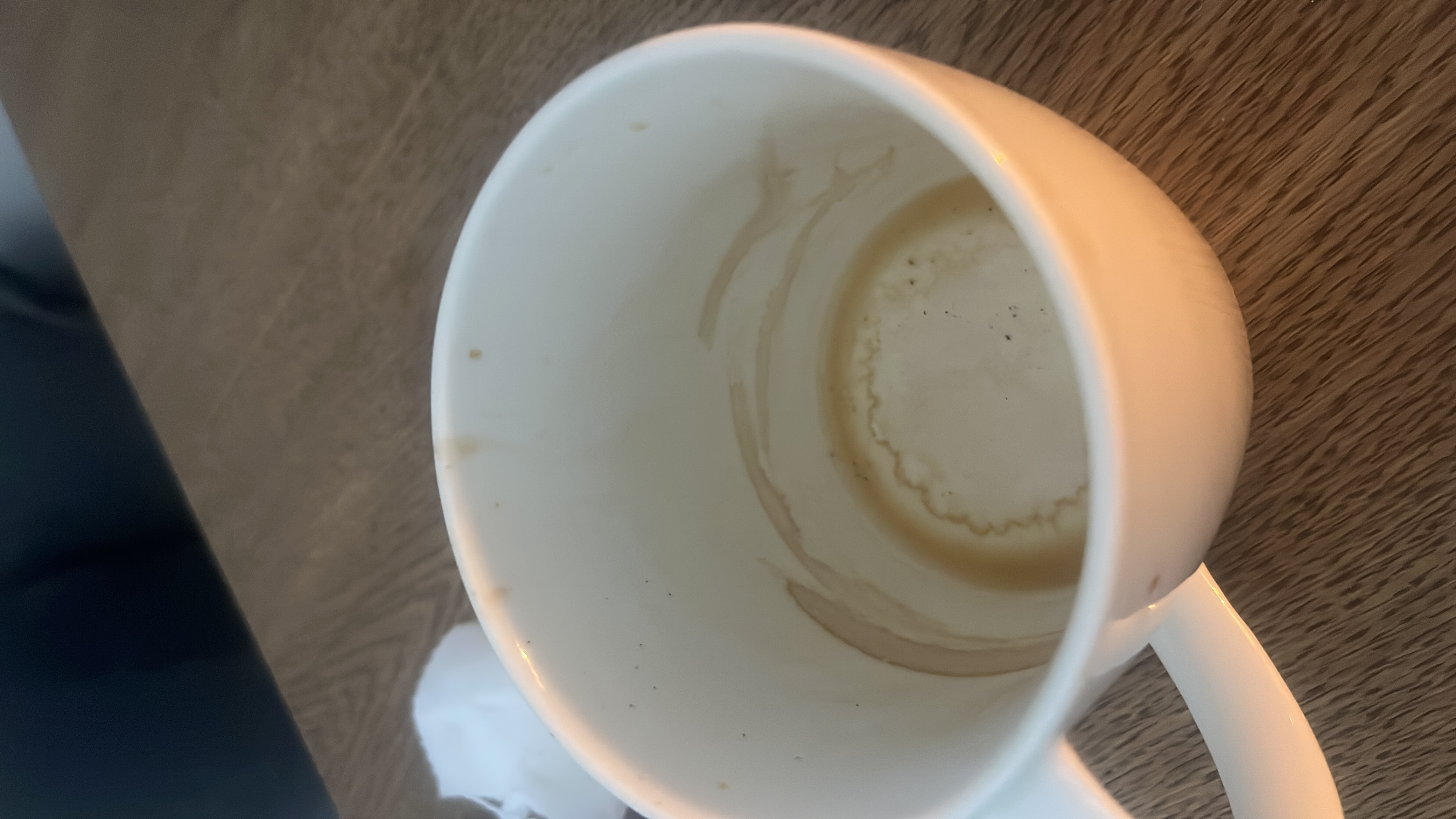 The image shows an empty cup with coffee residue, indicating that the beverage consumed was likely black coffee, which typically contains negligible calories, protein, carbs, and fats.