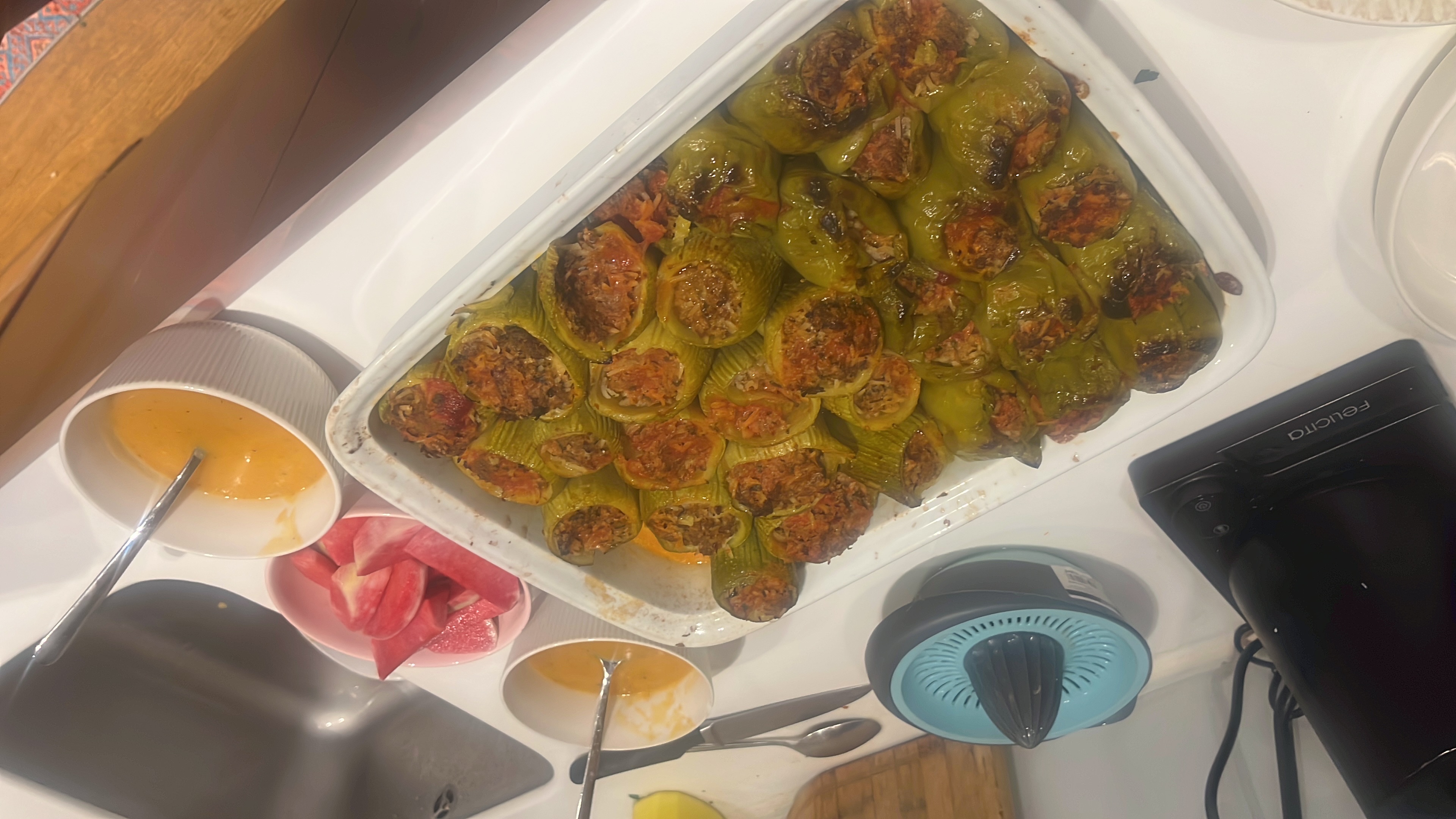 A dish of stuffed zucchini and rice with a tomato-based red sauce, served alongside a light salad.