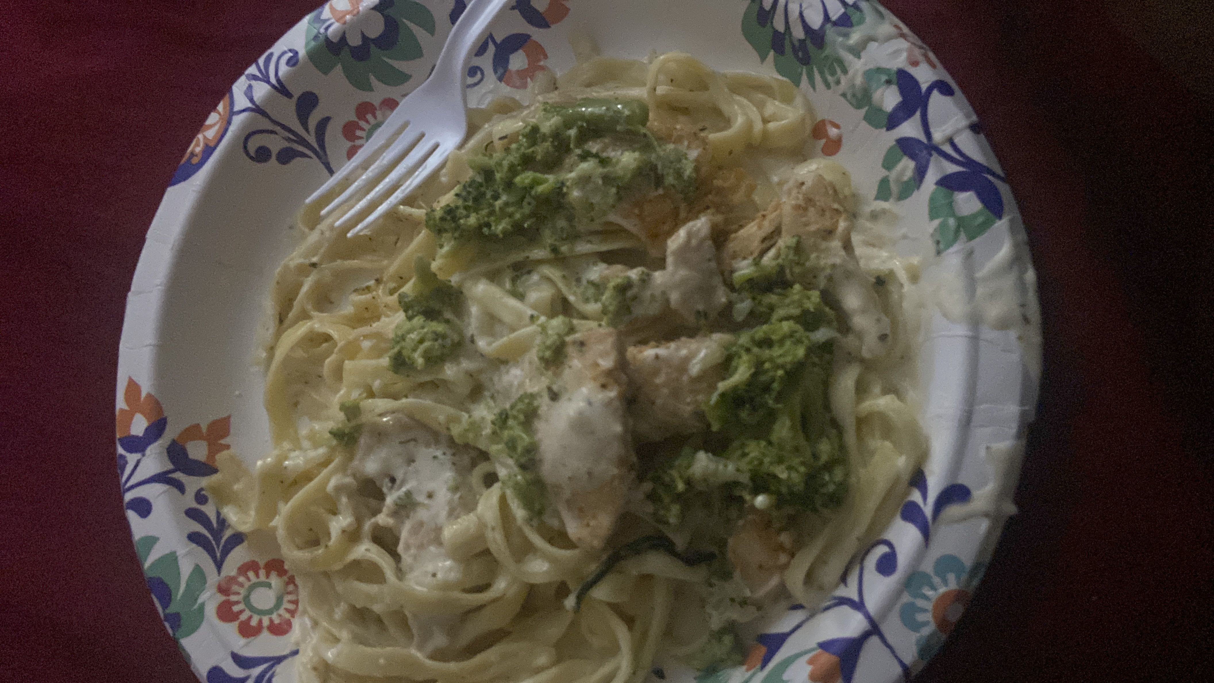 A plate of creamy chicken fettuccine pasta with broccoli, providing a balanced mix of protein, carbs, and fats.