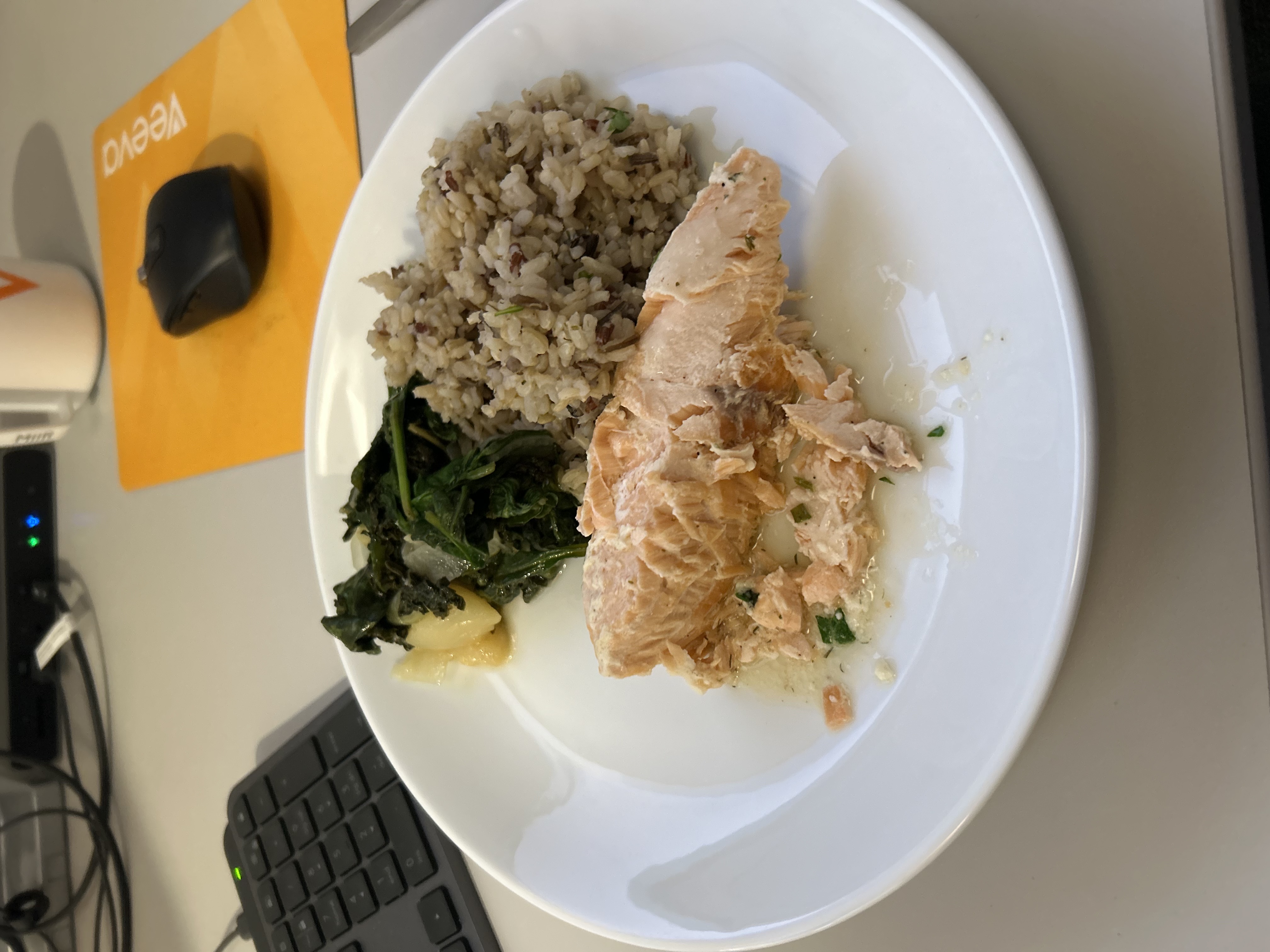 A balanced meal consisting of salmon, brown rice, and steamed greens, providing a good mix of protein, carbs, and fats.