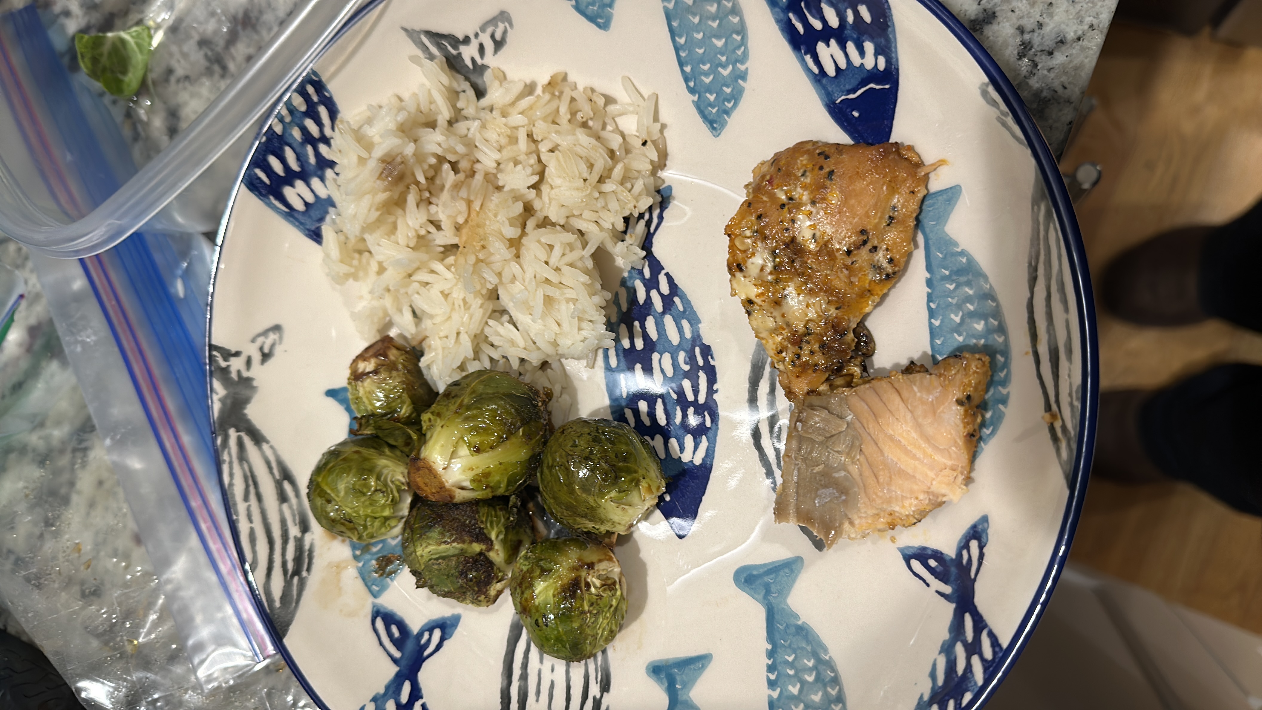 A balanced meal consisting of roasted Brussels sprouts, steamed rice, and seasoned salmon, providing a good mix of protein, carbs, and healthy fats.