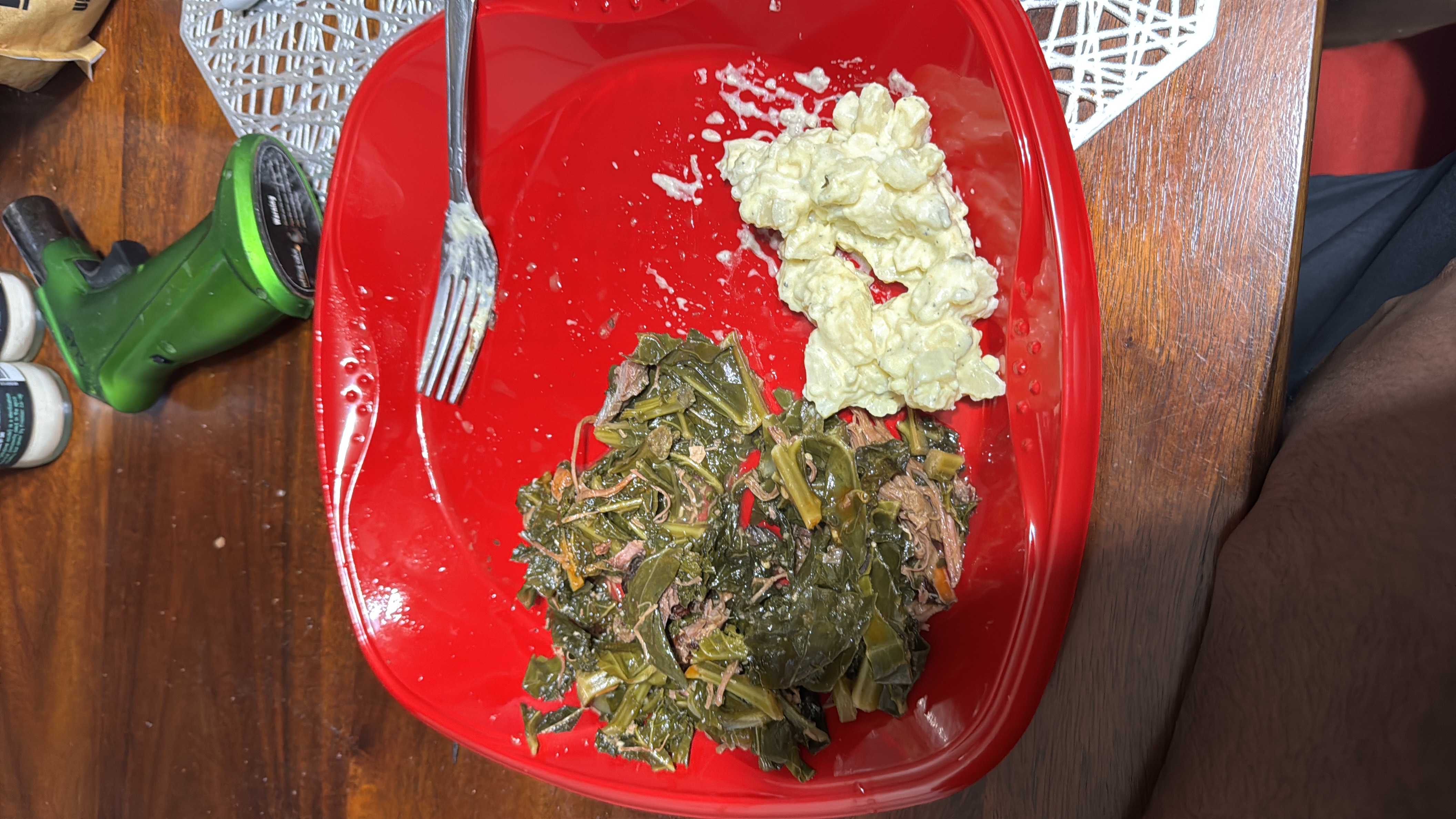 A meal consisting of collard greens with meat and potato salad, providing a balanced mix of protein, carbs, and fats.