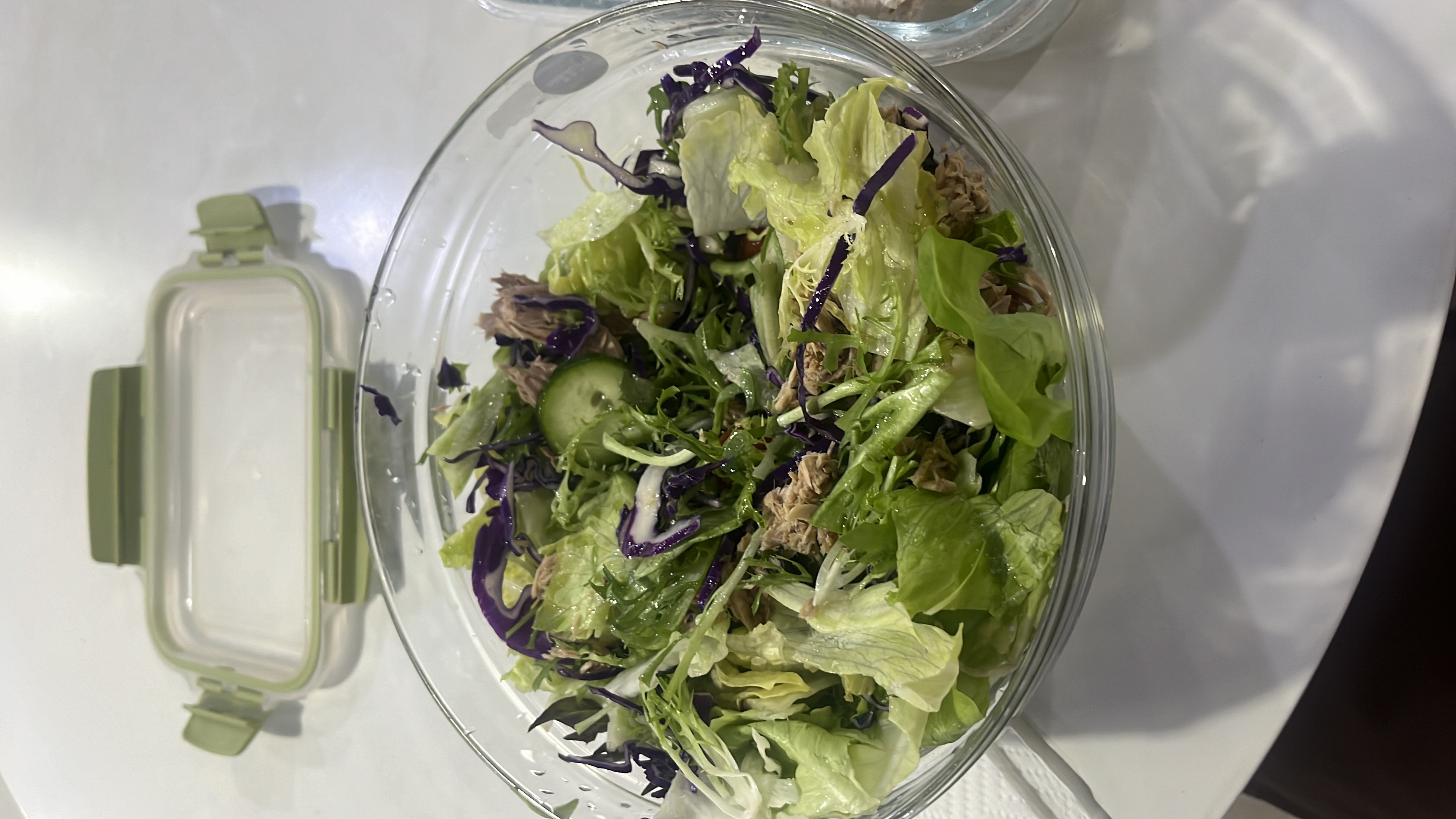A fresh salad containing lettuce, cucumber, red cabbage, tuna, and olive oil, offering a healthy and balanced nutritional profile.