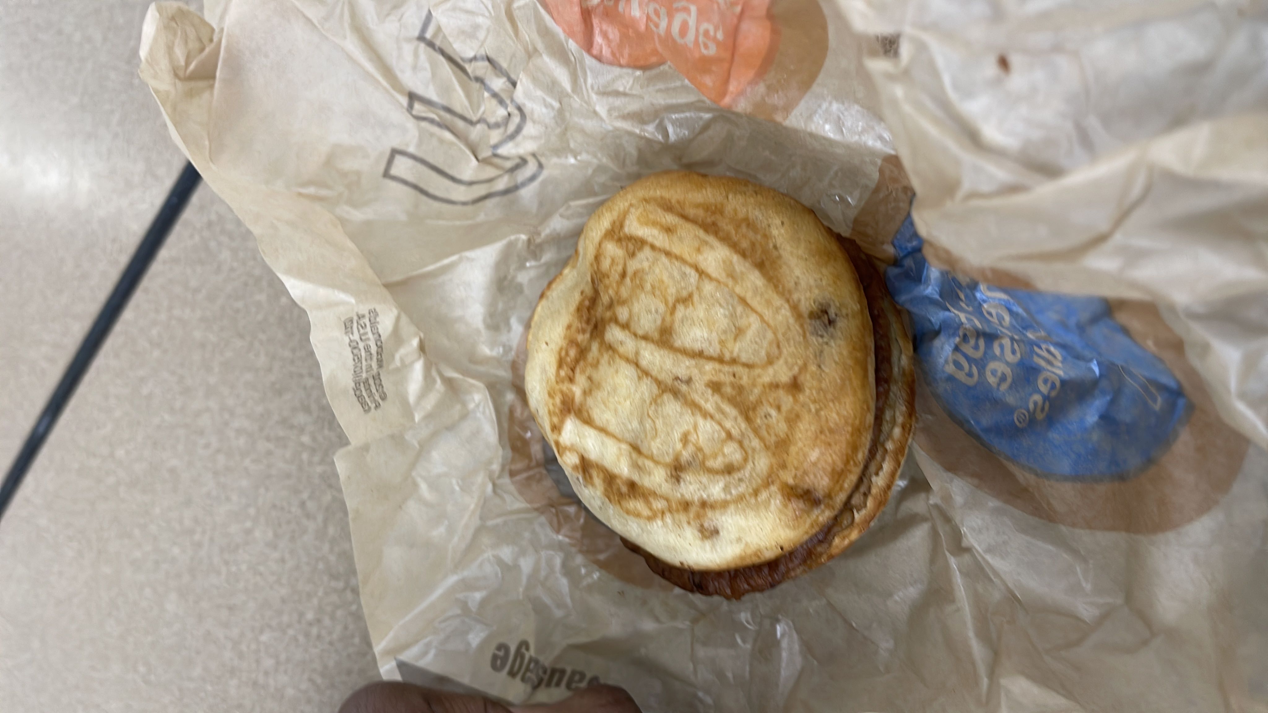 A breakfast sandwich consisting of an English muffin, egg, cheese, and sausage patty.