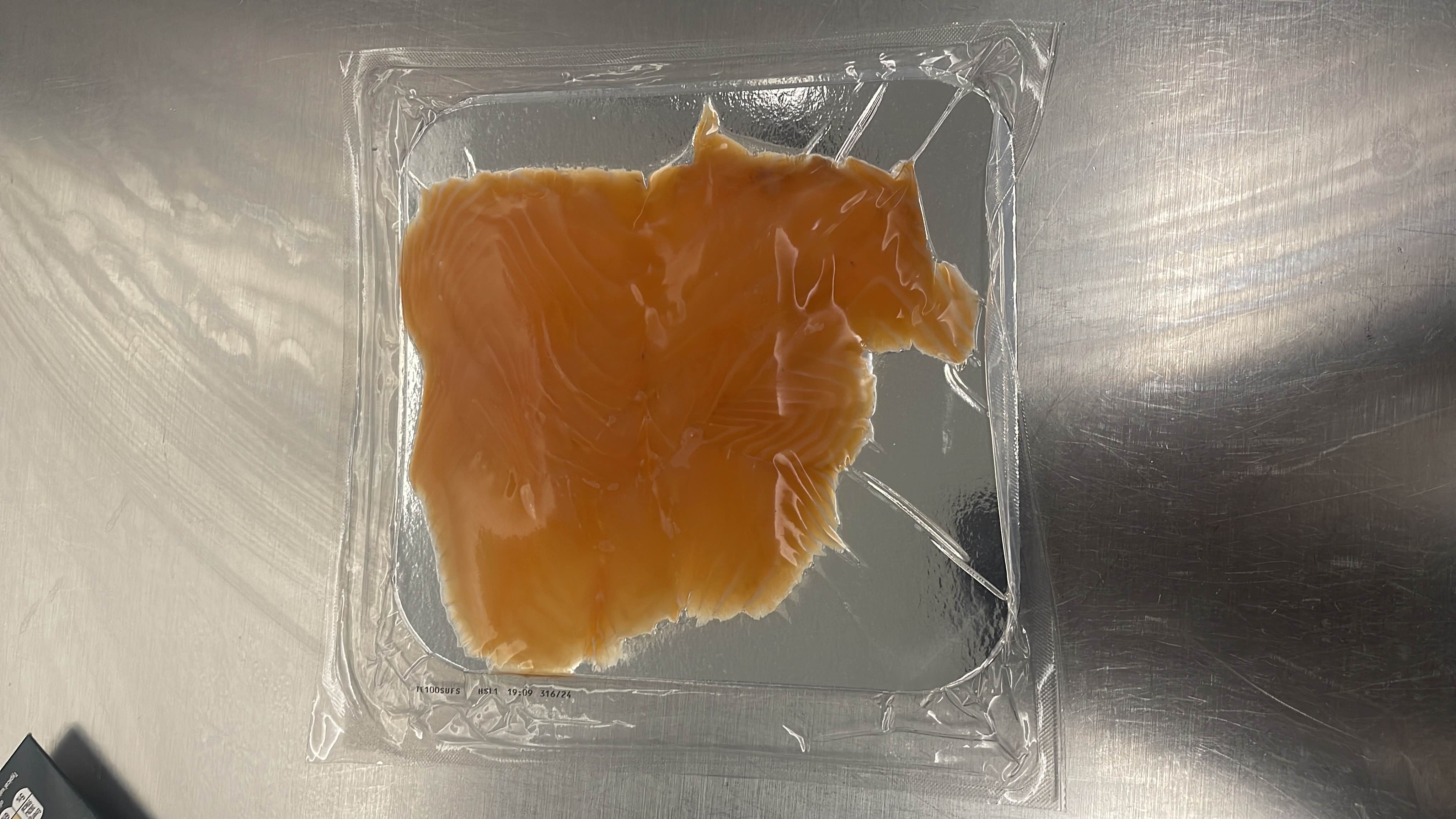 The image shows a packaged piece of salmon, which is a high-protein, low-carb food with moderate fat content.