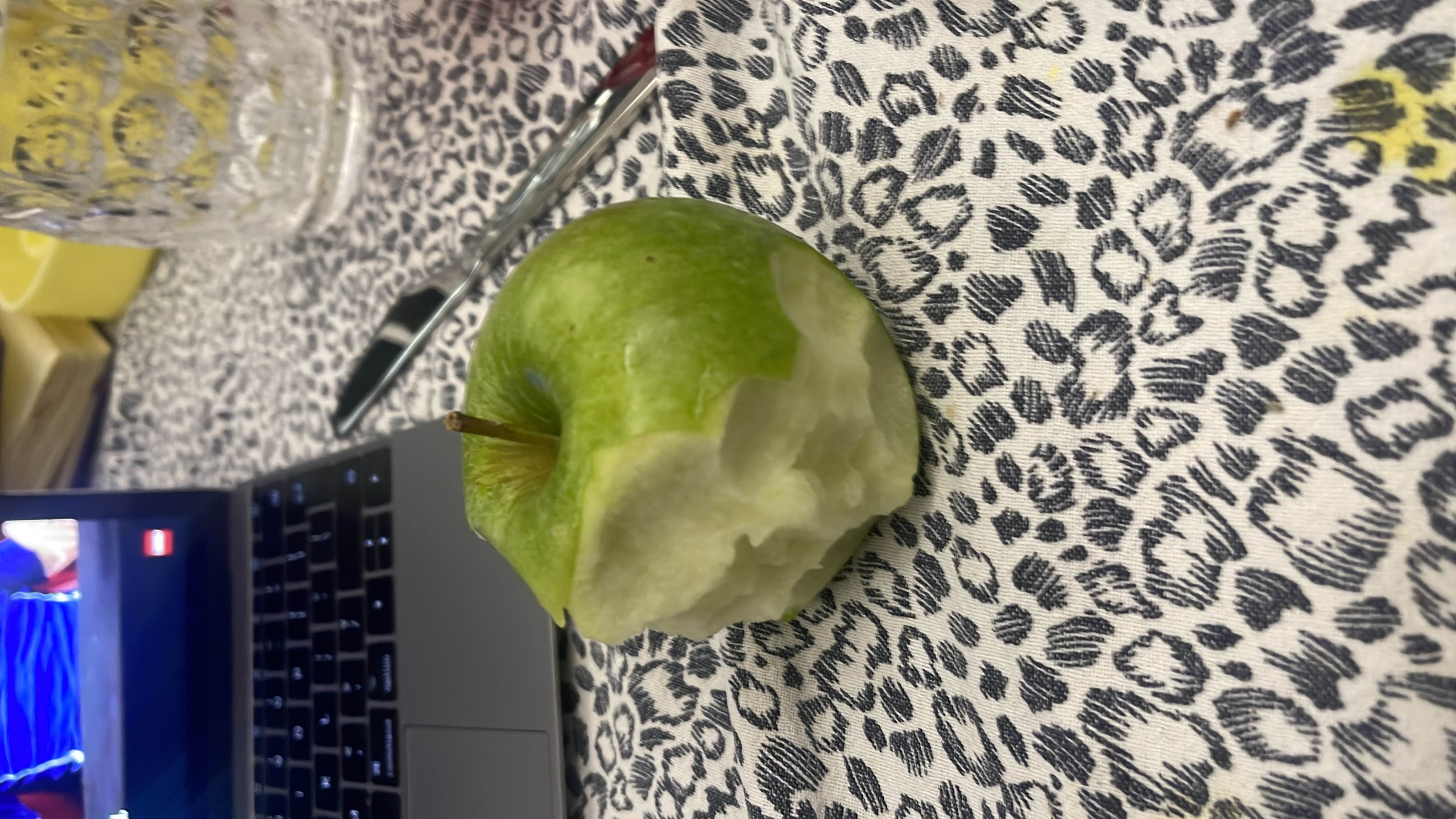 The image shows a partially eaten green apple, which is a low-calorie fruit rich in carbohydrates and fiber.