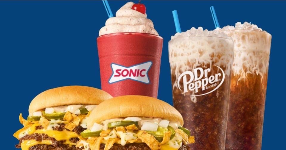 The image features a high-calorie meal consisting of cheeseburgers, a milkshake, and sodas.