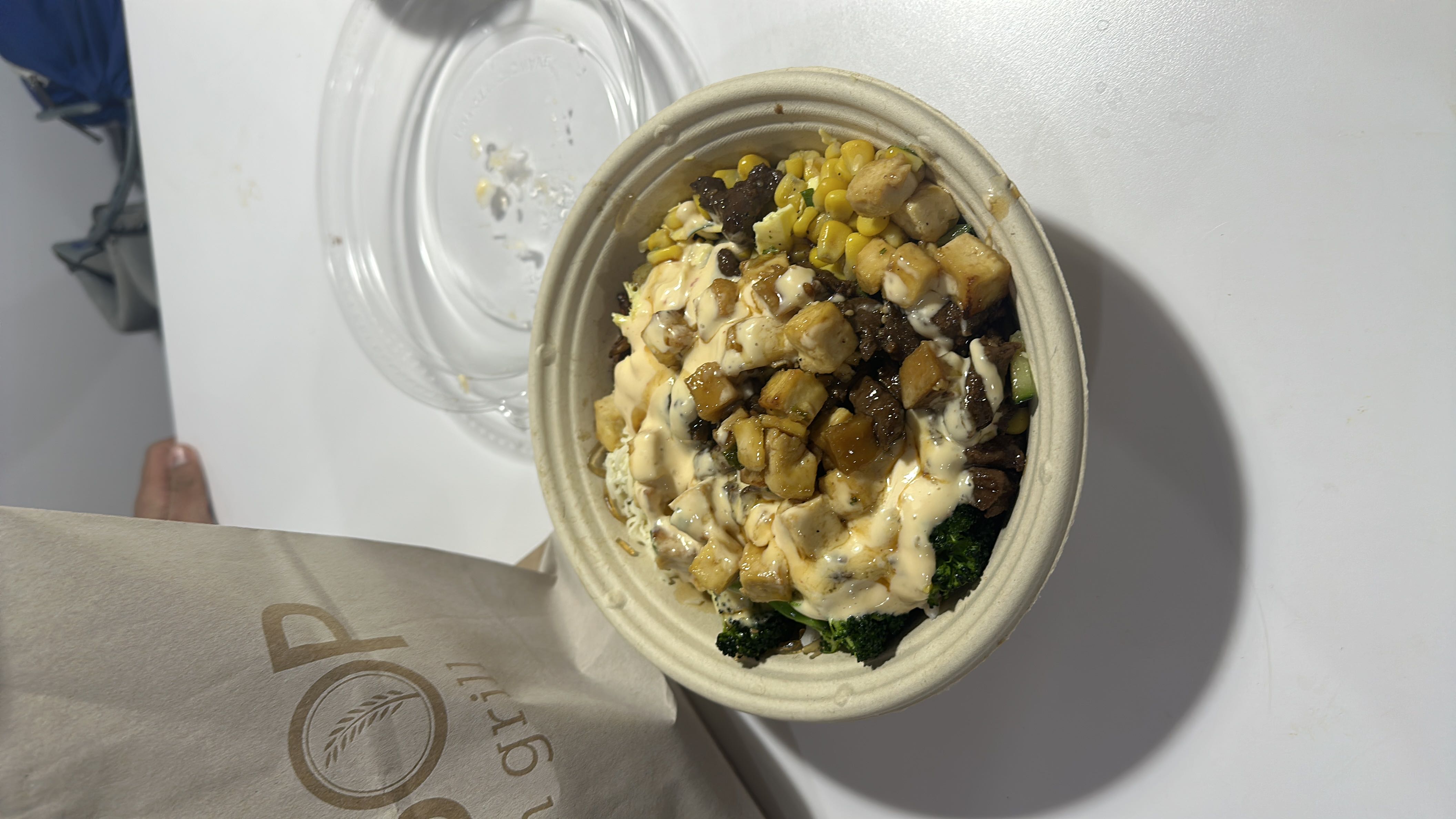 A balanced bowl containing broccoli, corn, tofu, beef, and a creamy sauce, offering a mix of protein, carbs, and fats.