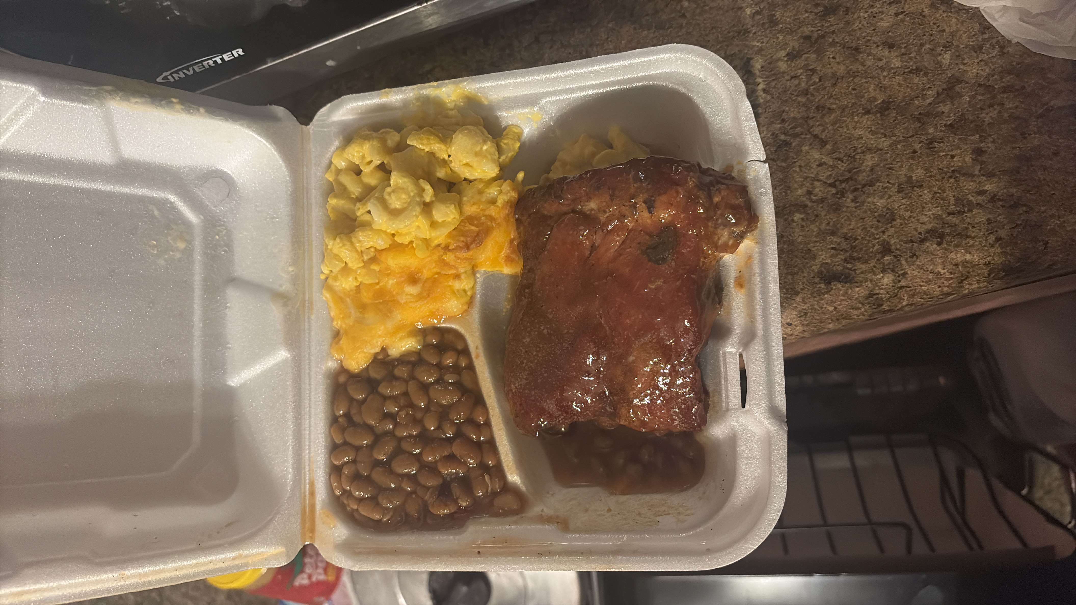 A meal consisting of barbecue ribs, baked beans, and mac and cheese, providing a balance of protein, carbs, and fats.