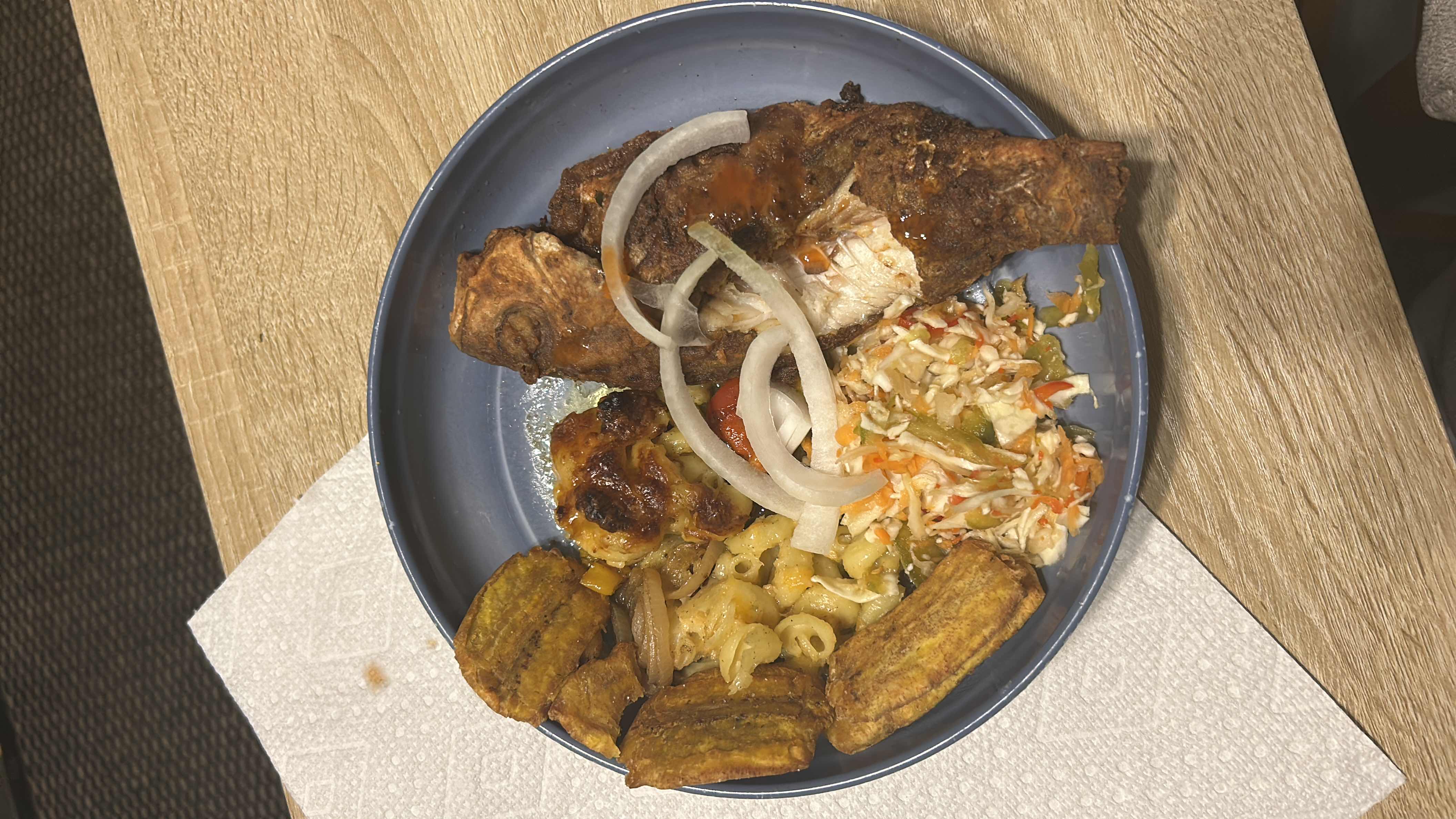 A balanced meal consisting of fried fish, fried plantains, macaroni and cheese, coleslaw, and onions with sauce.