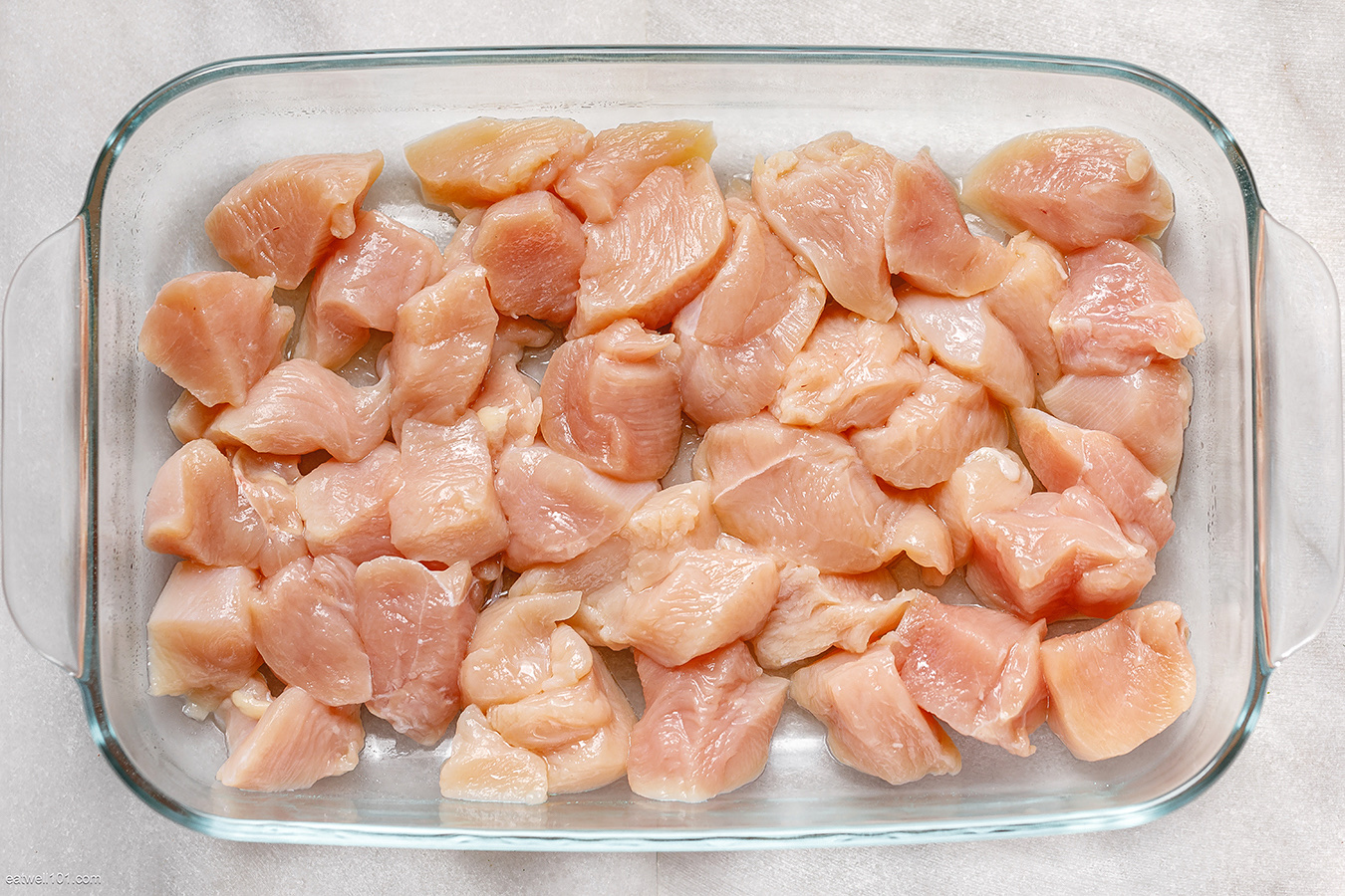 The image shows raw, diced chicken breast, which is a lean protein source with minimal fat and no carbohydrates.