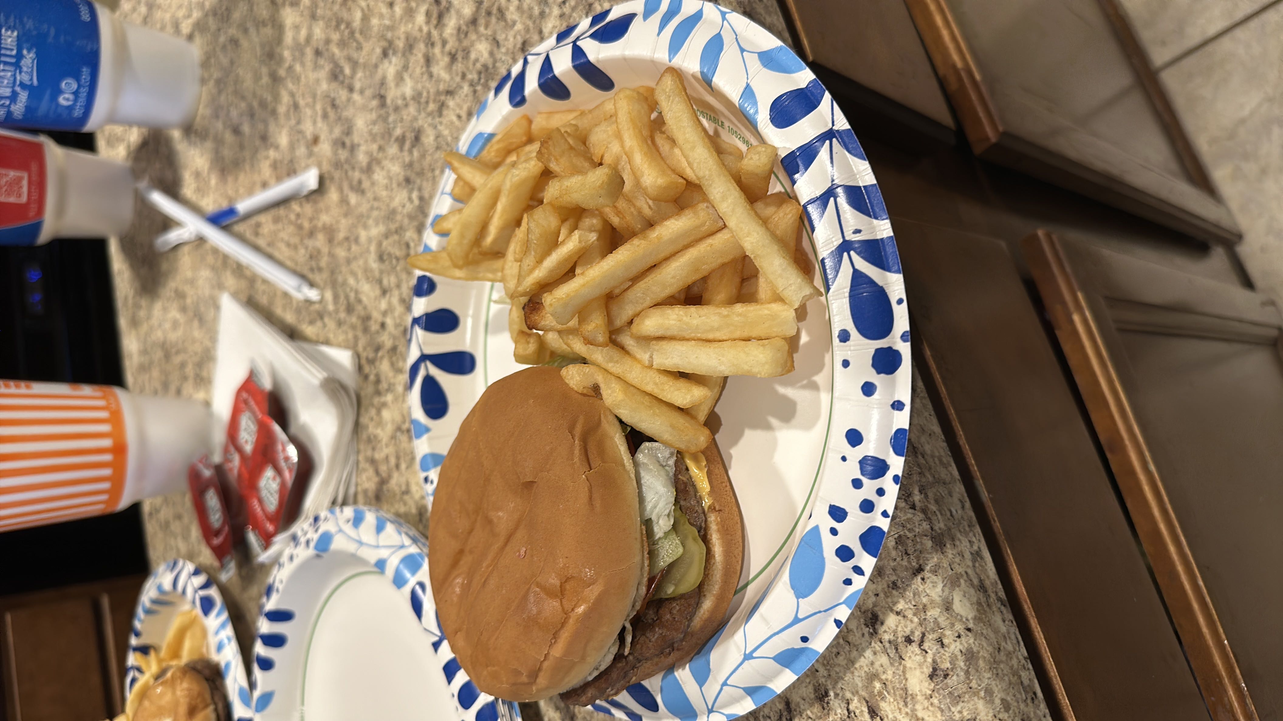 A meal consisting of a burger with pickles, lettuce, and cheese, served alongside a portion of French fries.
