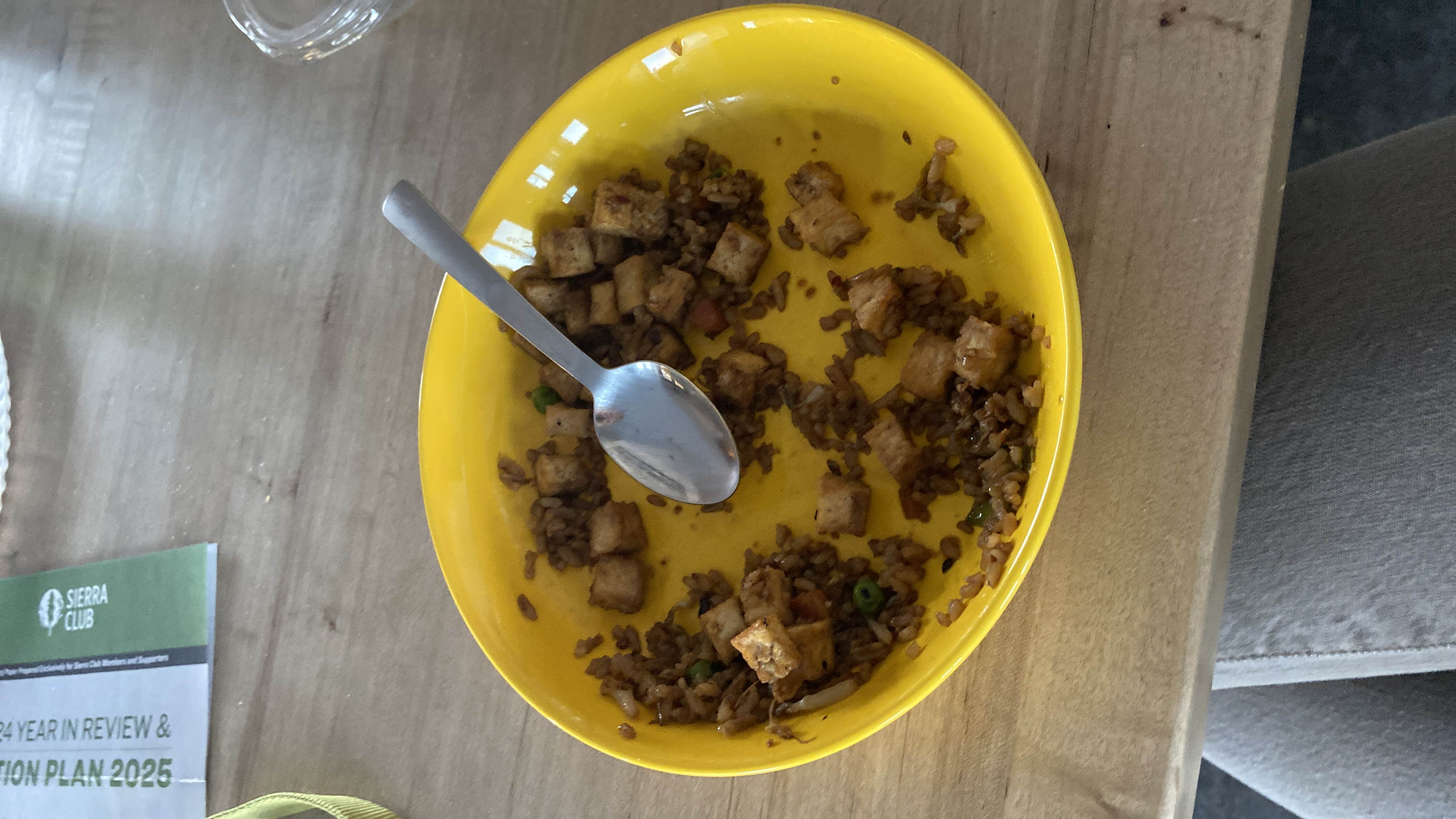A partially eaten dish of fried rice with tofu cubes, likely seasoned and containing vegetables.