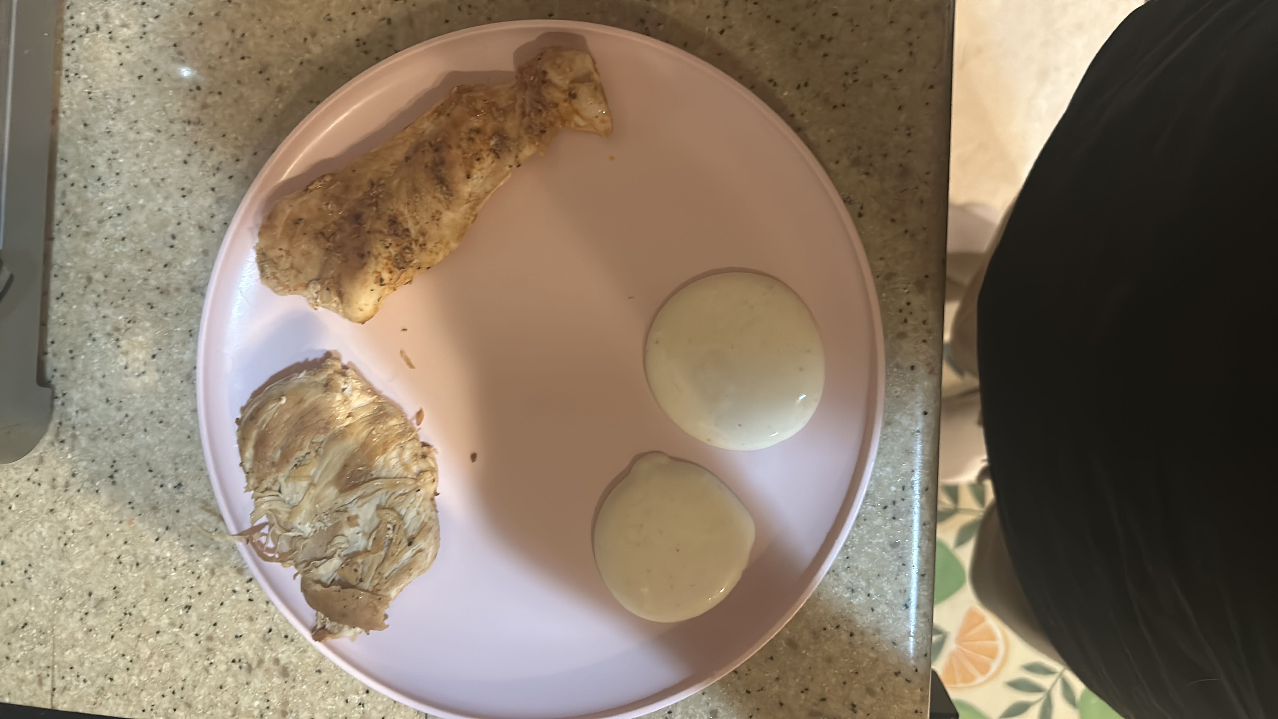 A plate containing grilled chicken breast and two servings of ranch dressing, providing a high-protein, moderate-fat meal.