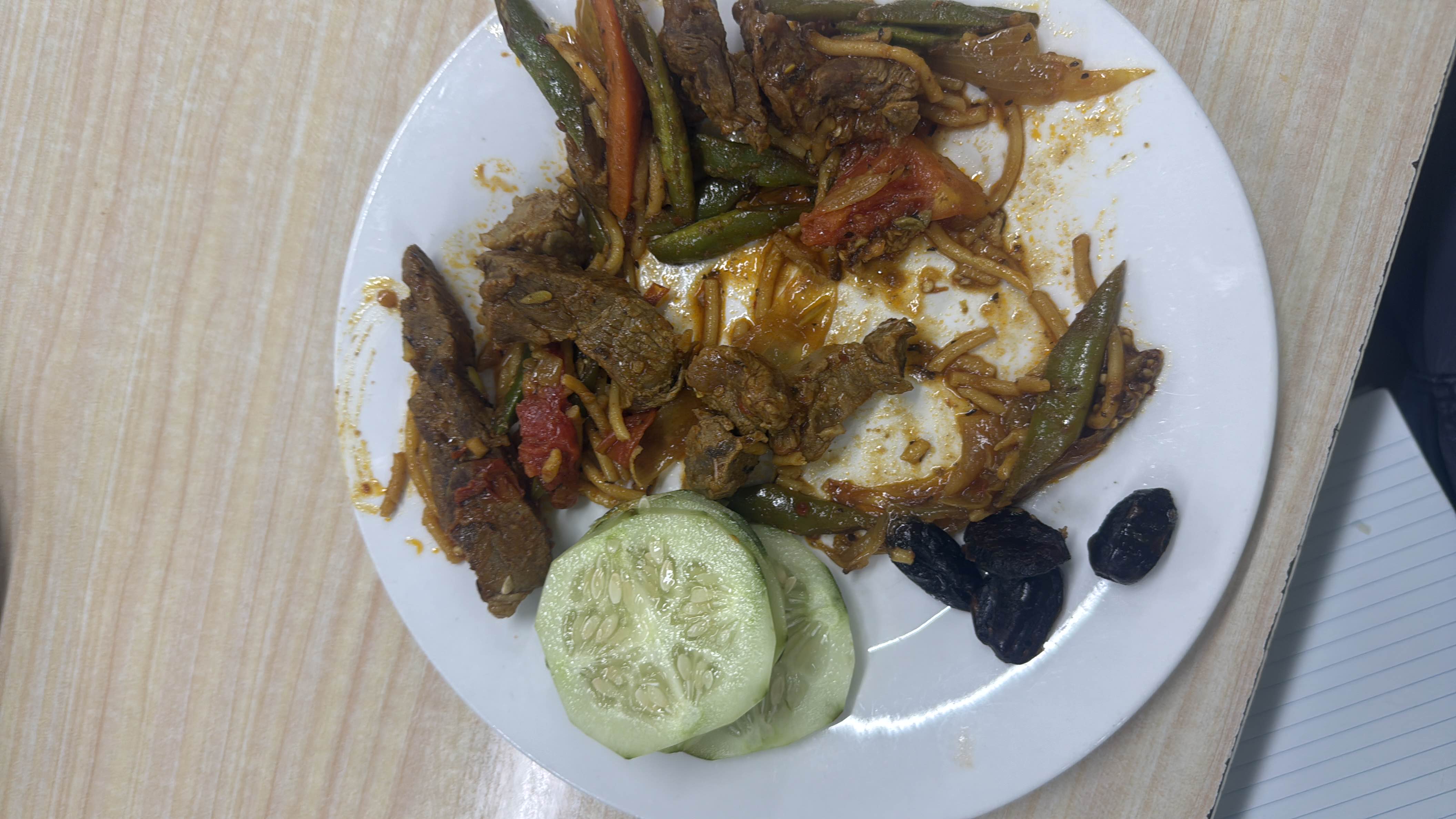 A plate containing beef, mixed vegetables, cucumber slices, and dates, providing a balanced mix of protein, carbs, and fats.