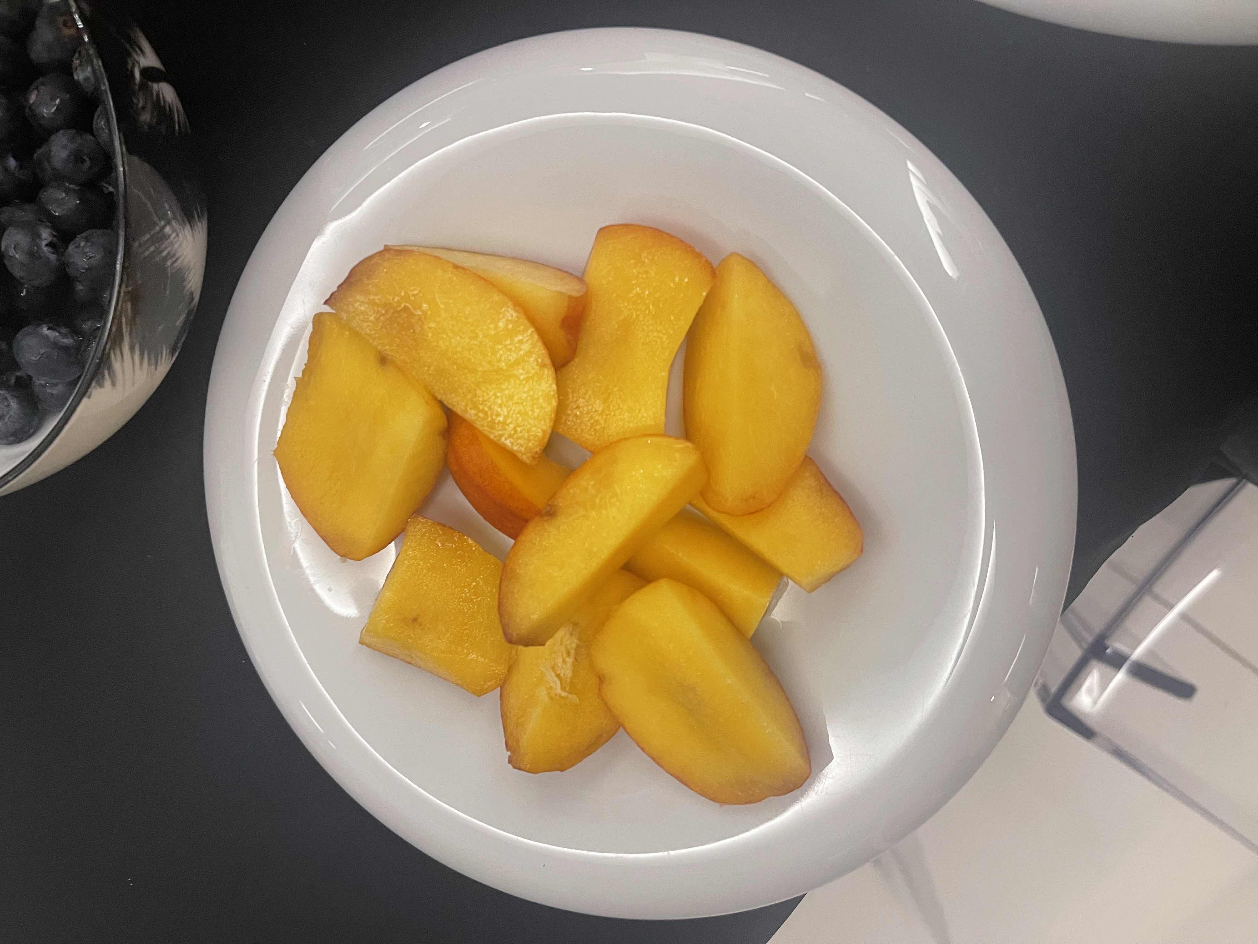 The image shows a plate of fresh peach slices, which are low in calories and rich in carbohydrates, making them a healthy snack option.