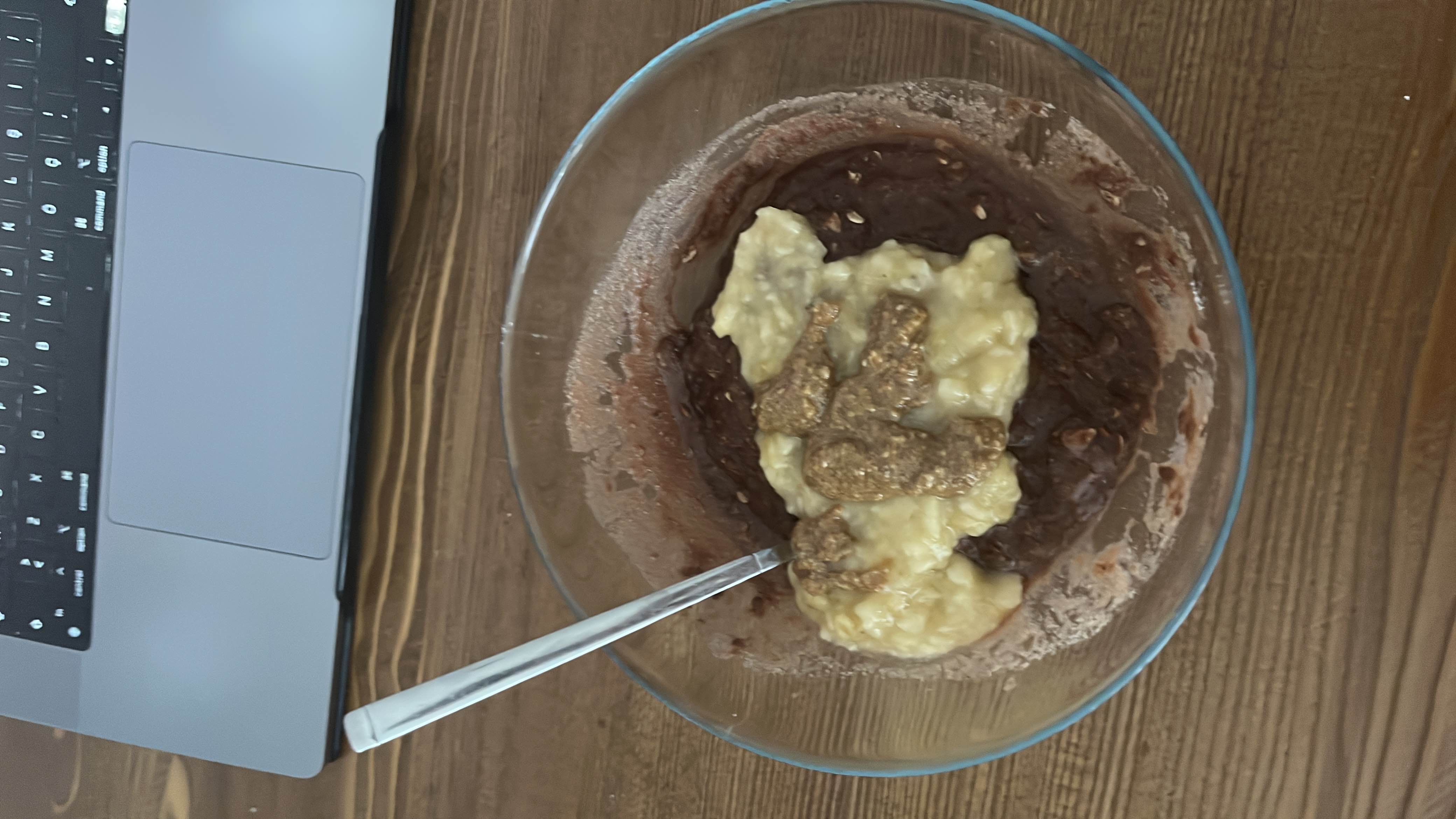 A bowl of chocolate oatmeal topped with mashed banana, peanut butter, rice cream, and whey protein, providing a balanced mix of carbs, protein, and fats.