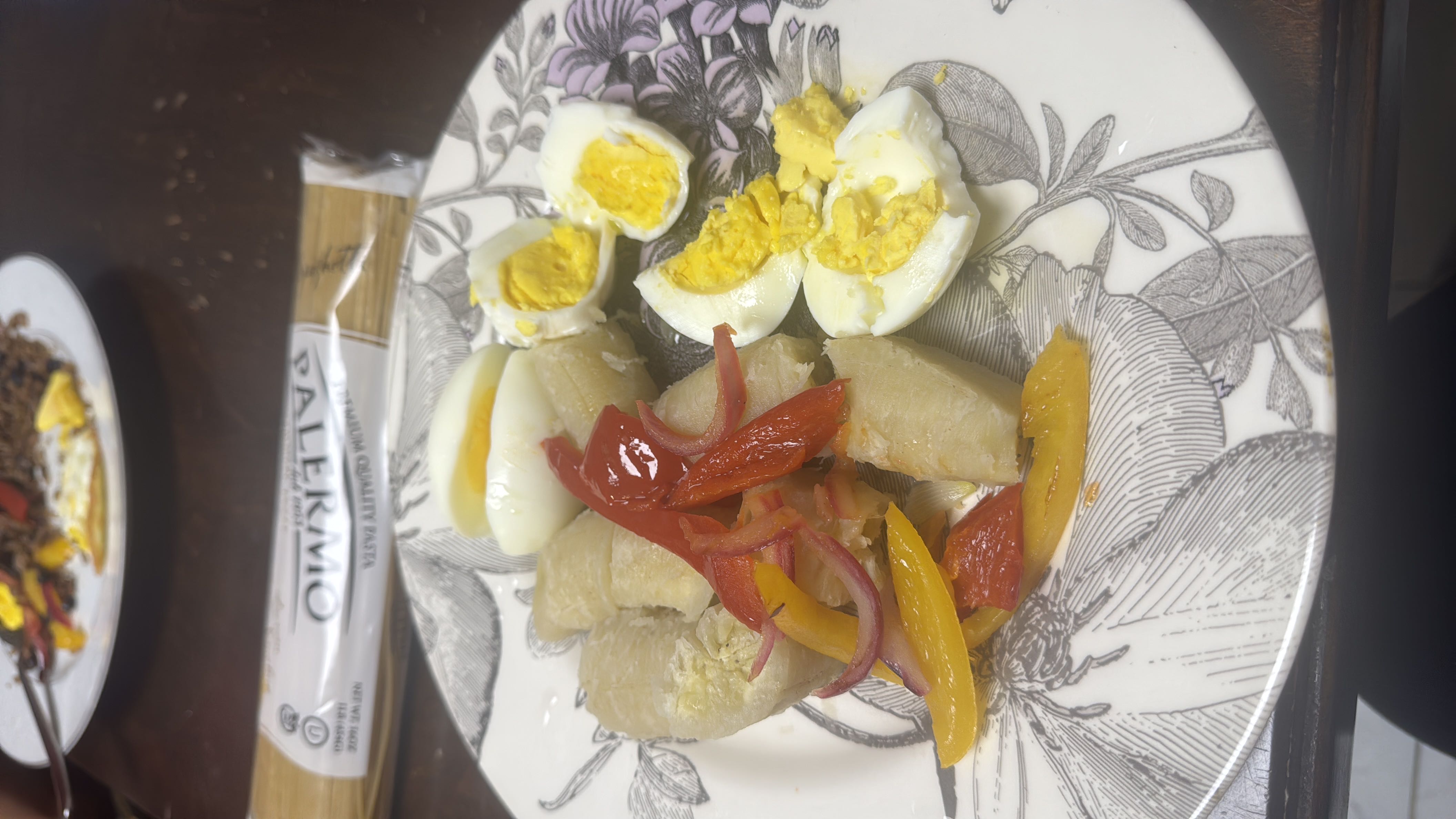 A plate containing boiled plantains, boiled eggs, and sautéed peppers and onions, offering a balanced meal with moderate calories and a good health score.