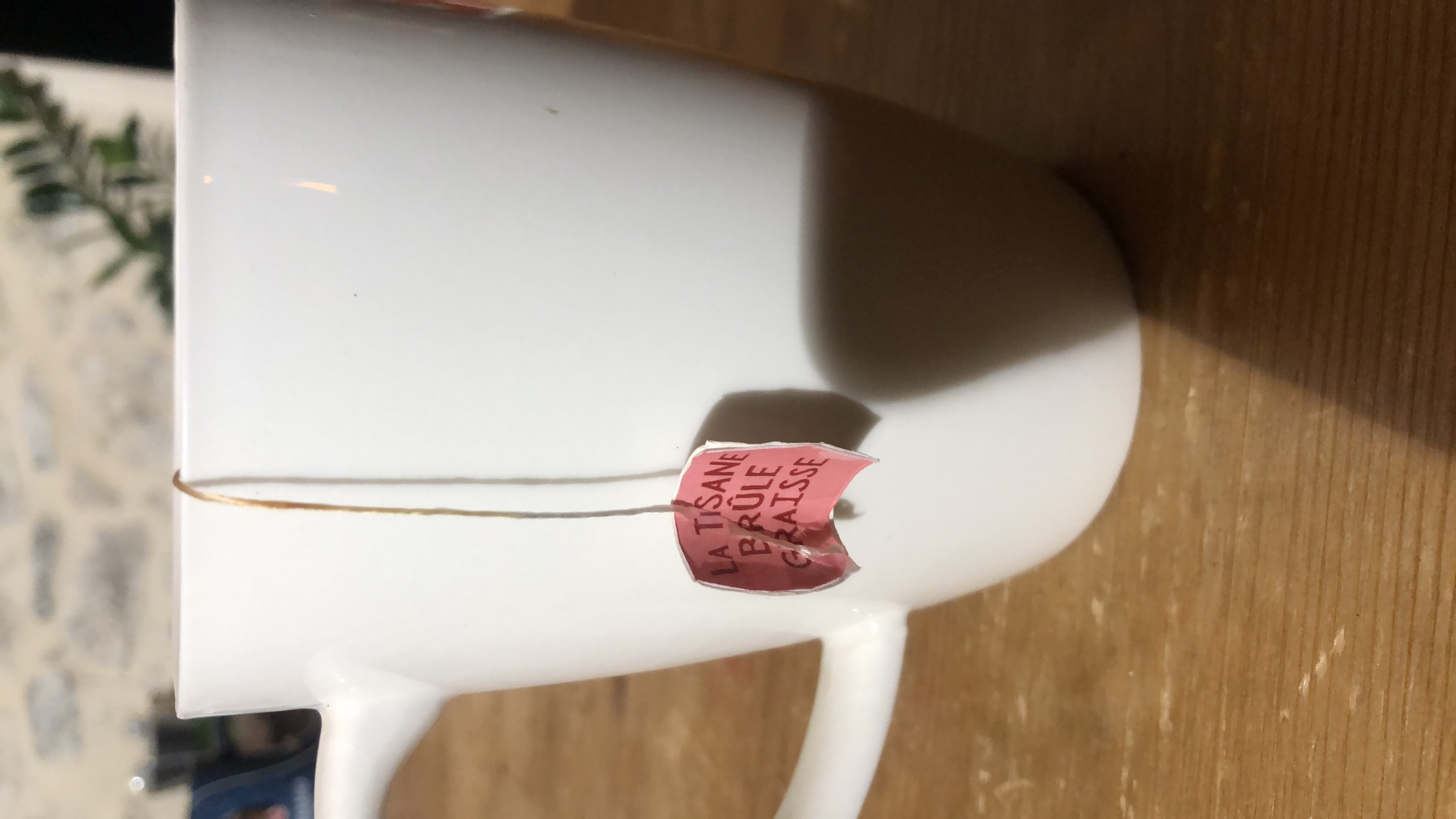 A cup of herbal tea labeled as 'La Tisane Brûle Graisse,' which translates to 'Fat-Burning Tea,' suggesting a low-calorie beverage with potential health benefits.