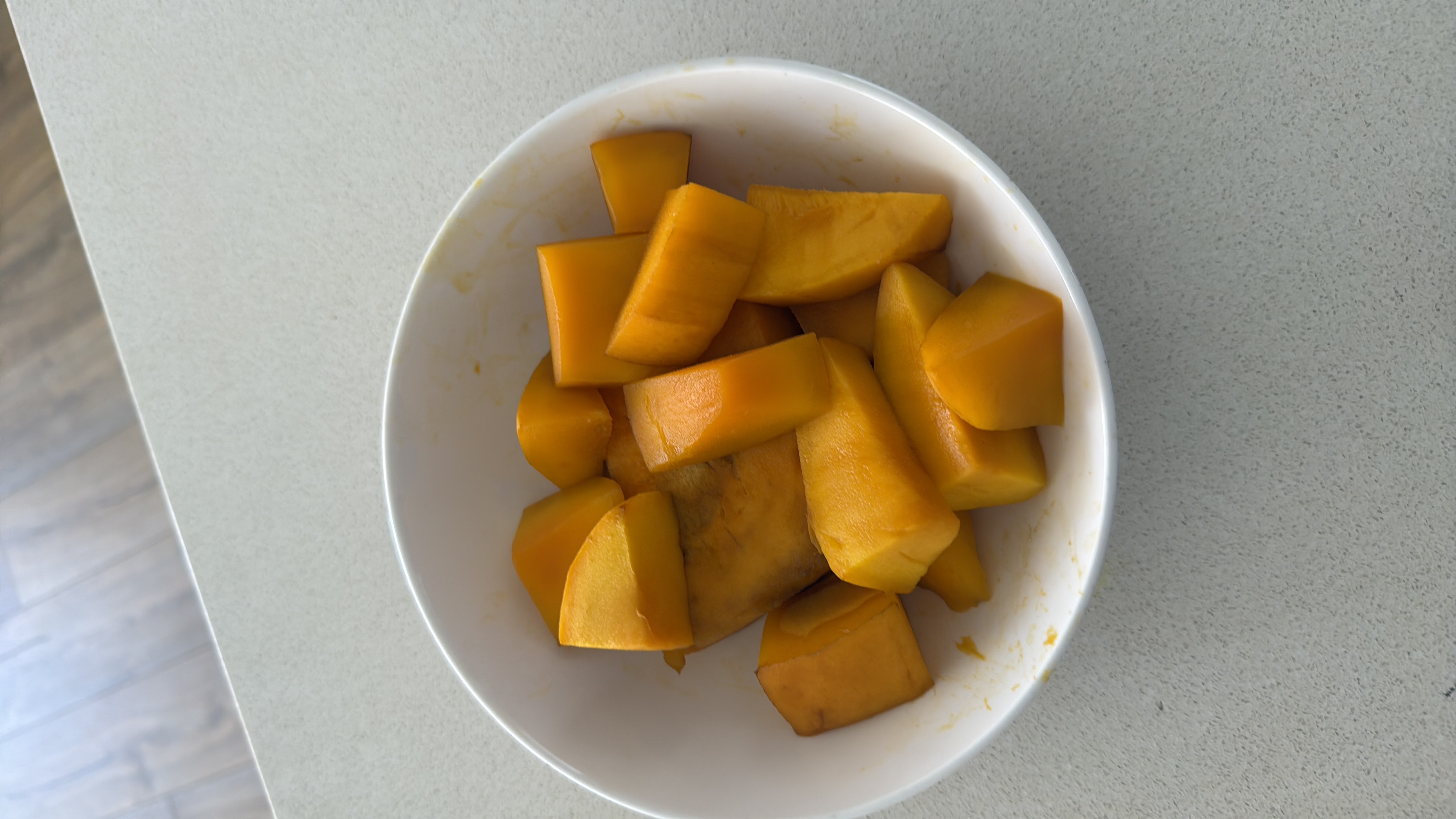 A bowl of fresh mango pieces, a nutrient-rich fruit high in carbohydrates and low in fats.
