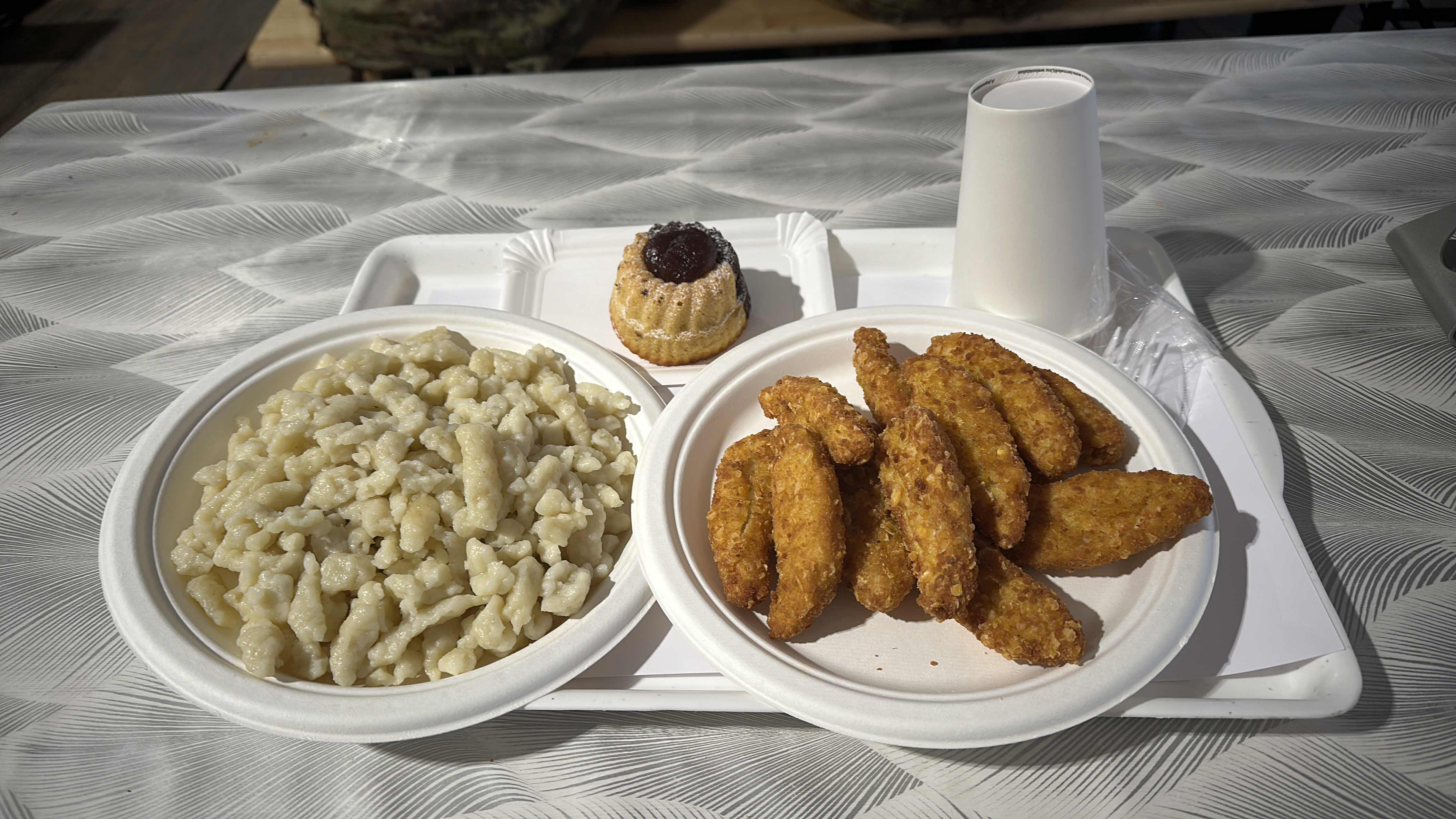 The meal consists of fried chicken strips, pasta with sauce, and a cupcake, providing a balanced mix of protein, carbs, and fats.