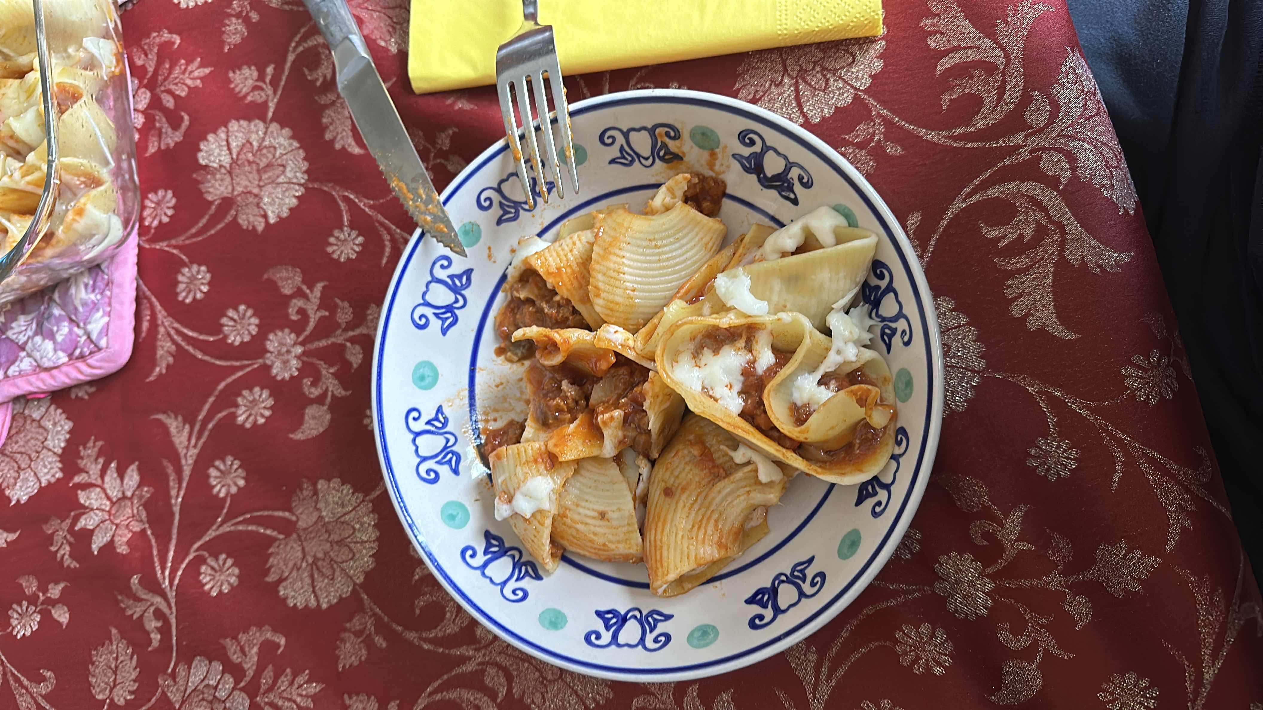 A plate of stuffed pasta shells with ground meat, cheese, and tomato sauce, served as a hearty meal.