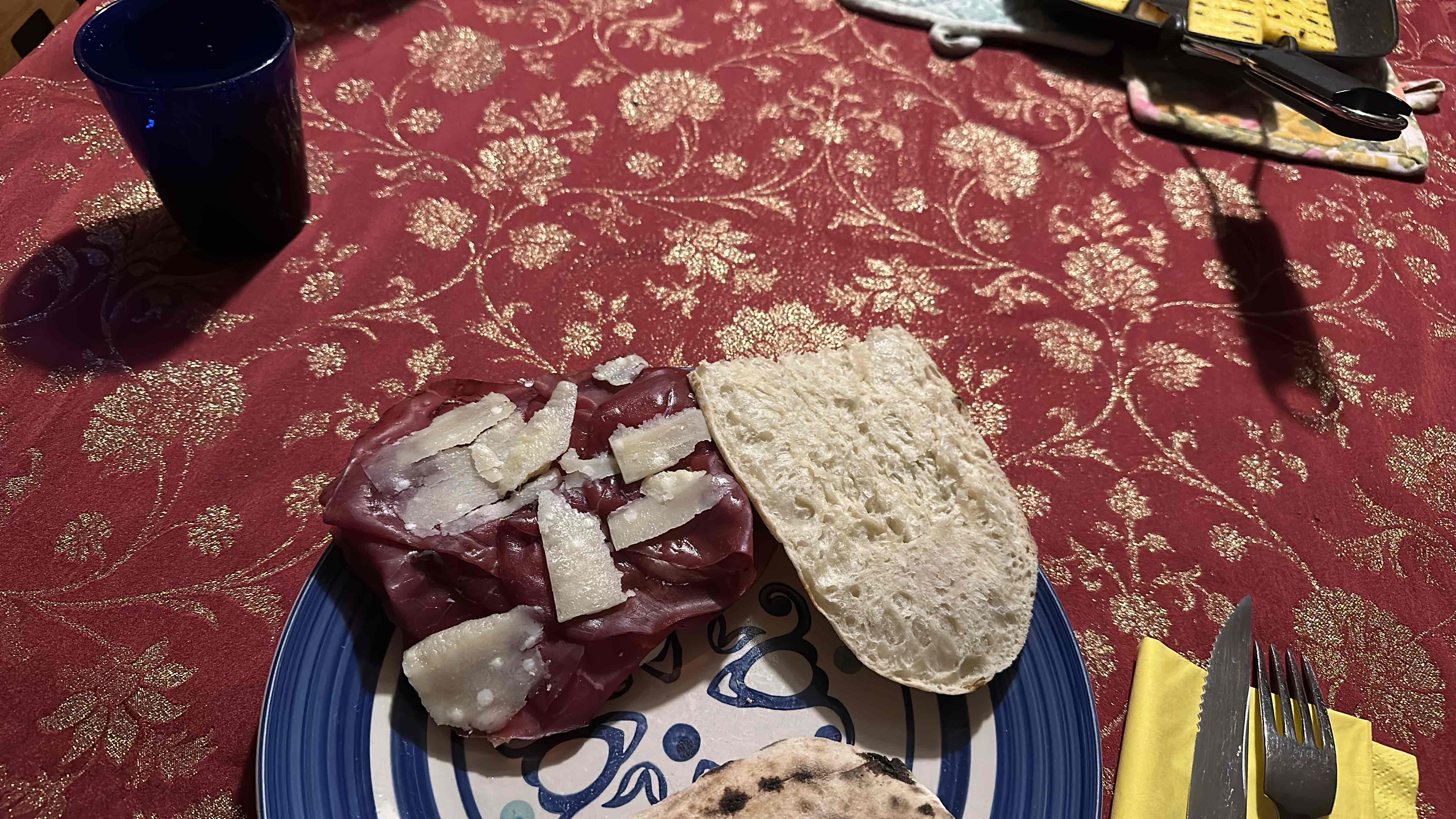 A meal consisting of bread, cured meat, and cheese, served on a decorative plate.