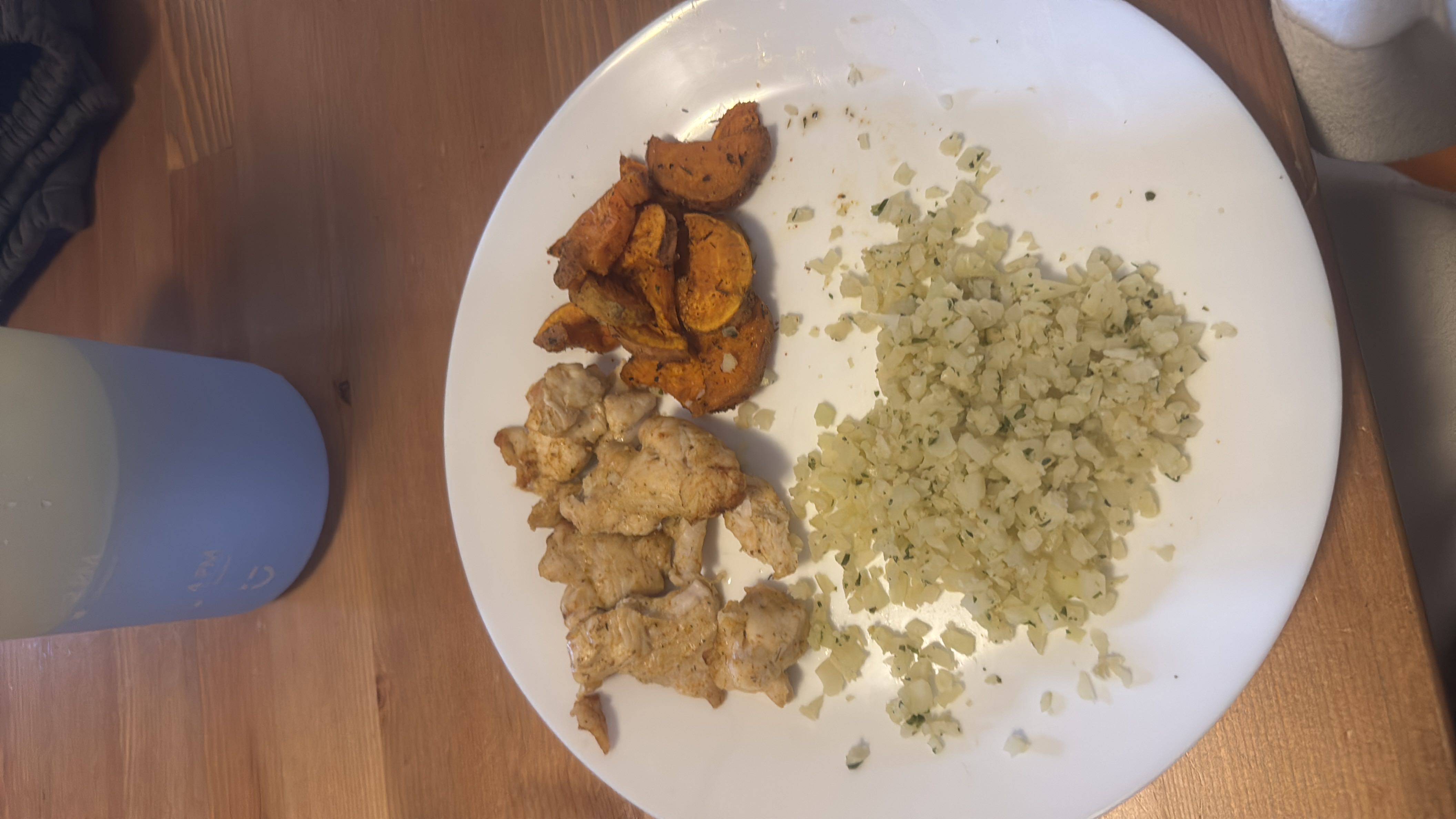 A balanced meal consisting of grilled chicken, roasted sweet potatoes, and seasoned cauliflower rice.