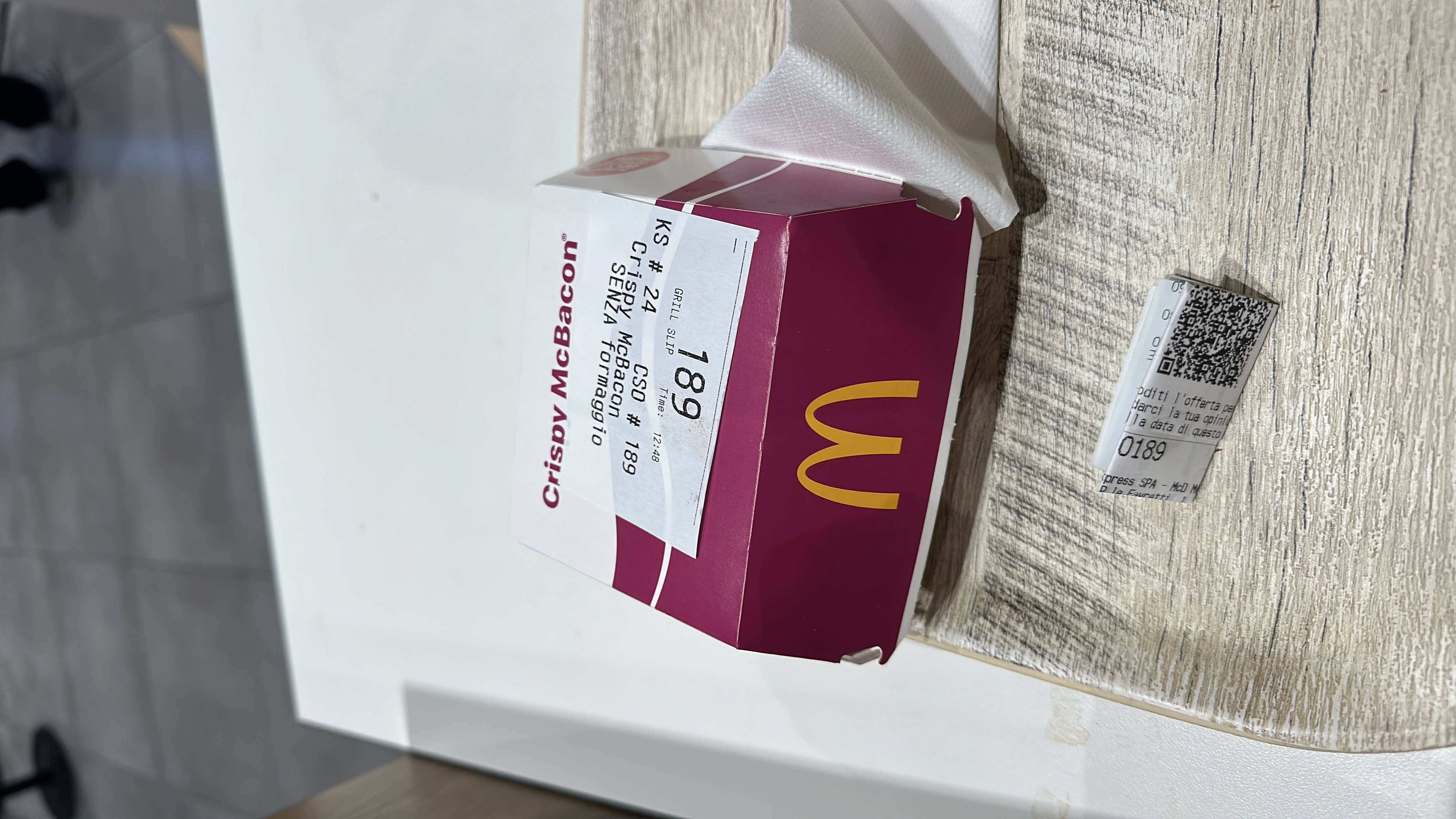 The image shows a Crispy McBacon meal box, likely containing a burger with bacon, cheese, and a bun.