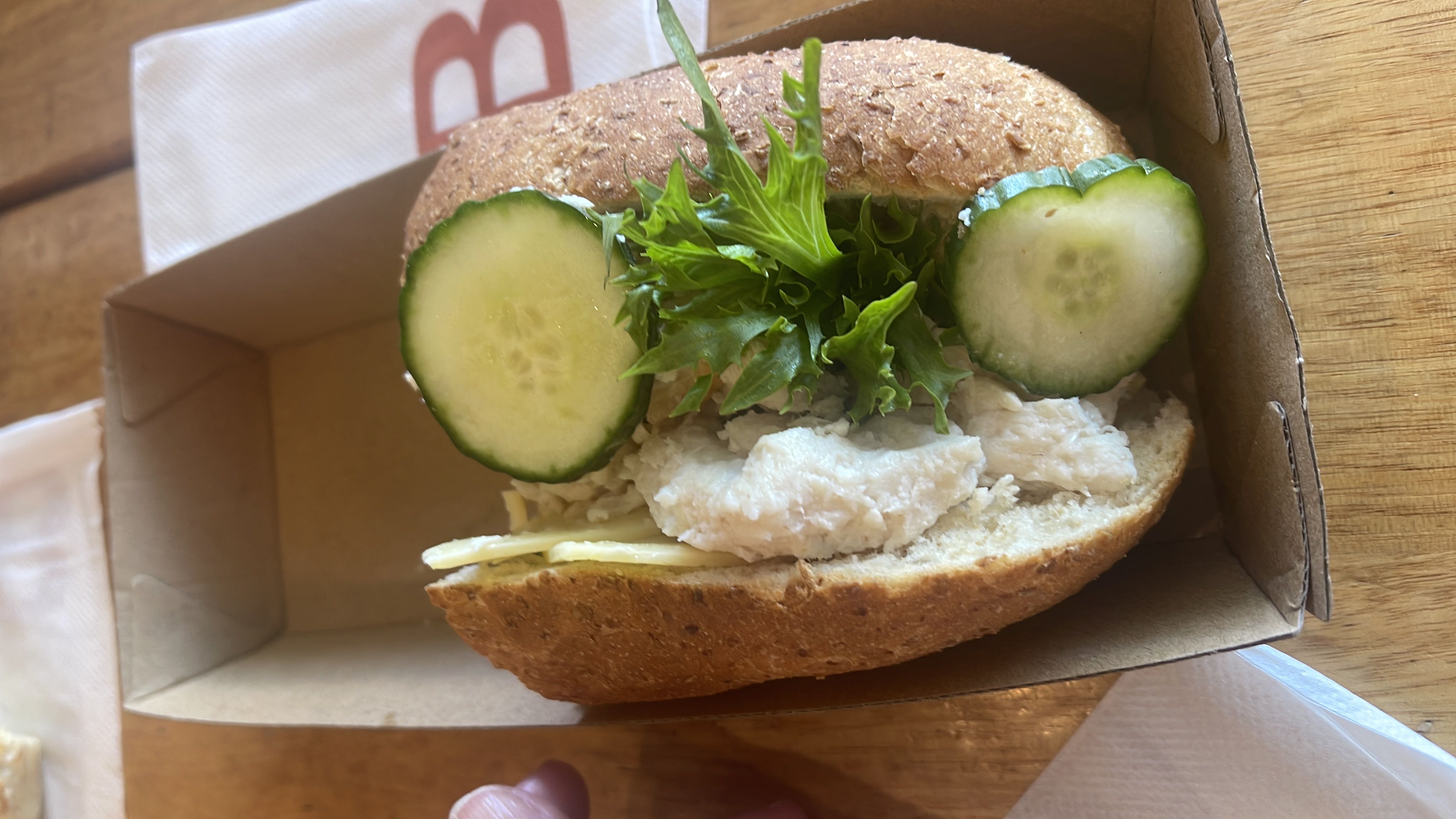 A healthy sandwich made with whole grain bread, chicken, cucumber, lettuce, and butter.