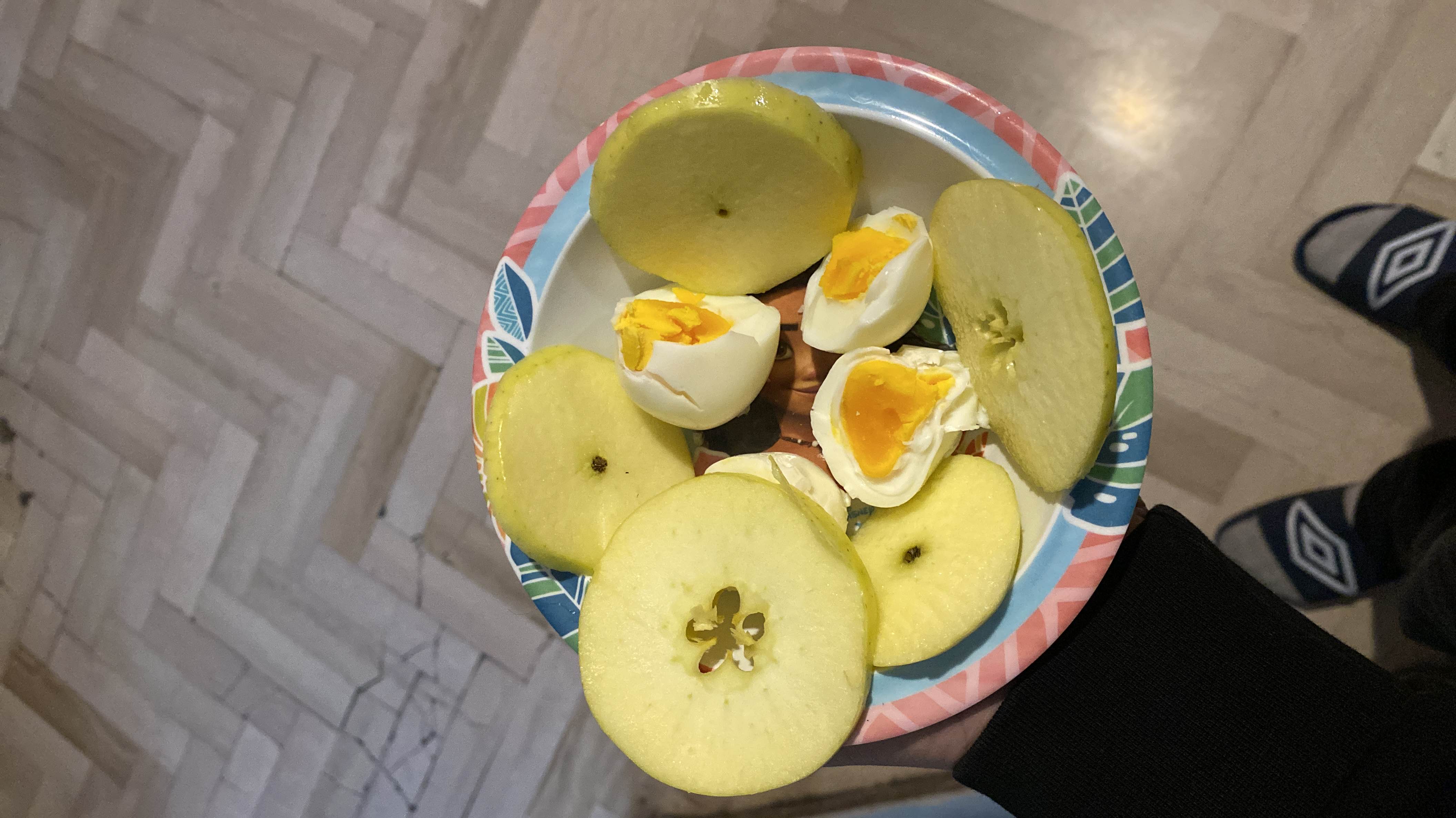 A plate containing sliced apple and boiled eggs, providing a balanced mix of protein, carbs, and fats.