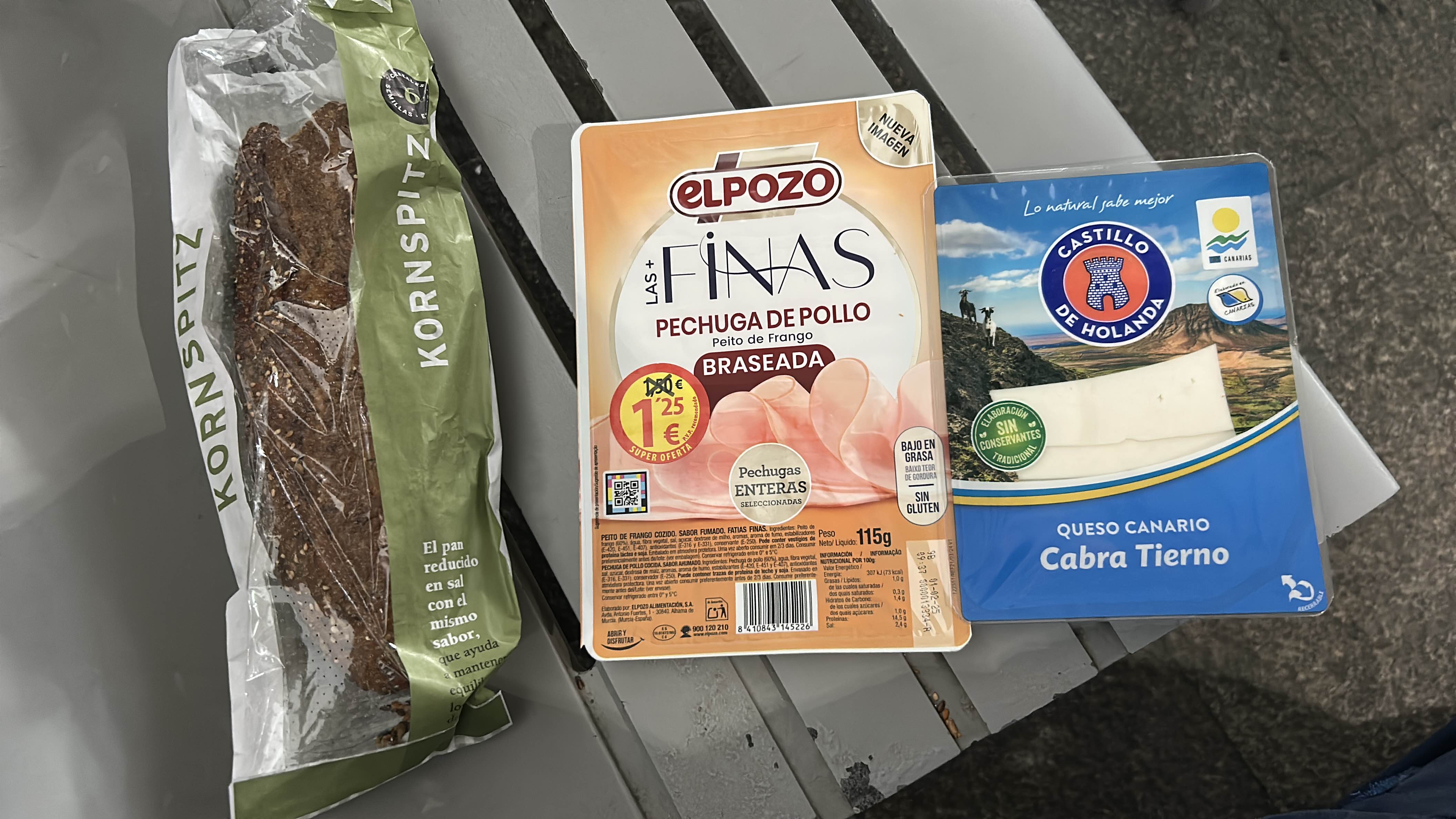 The image shows a combination of Kornspitz bread, chicken breast slices, and goat cheese, providing a balanced mix of protein, carbs, and fats.