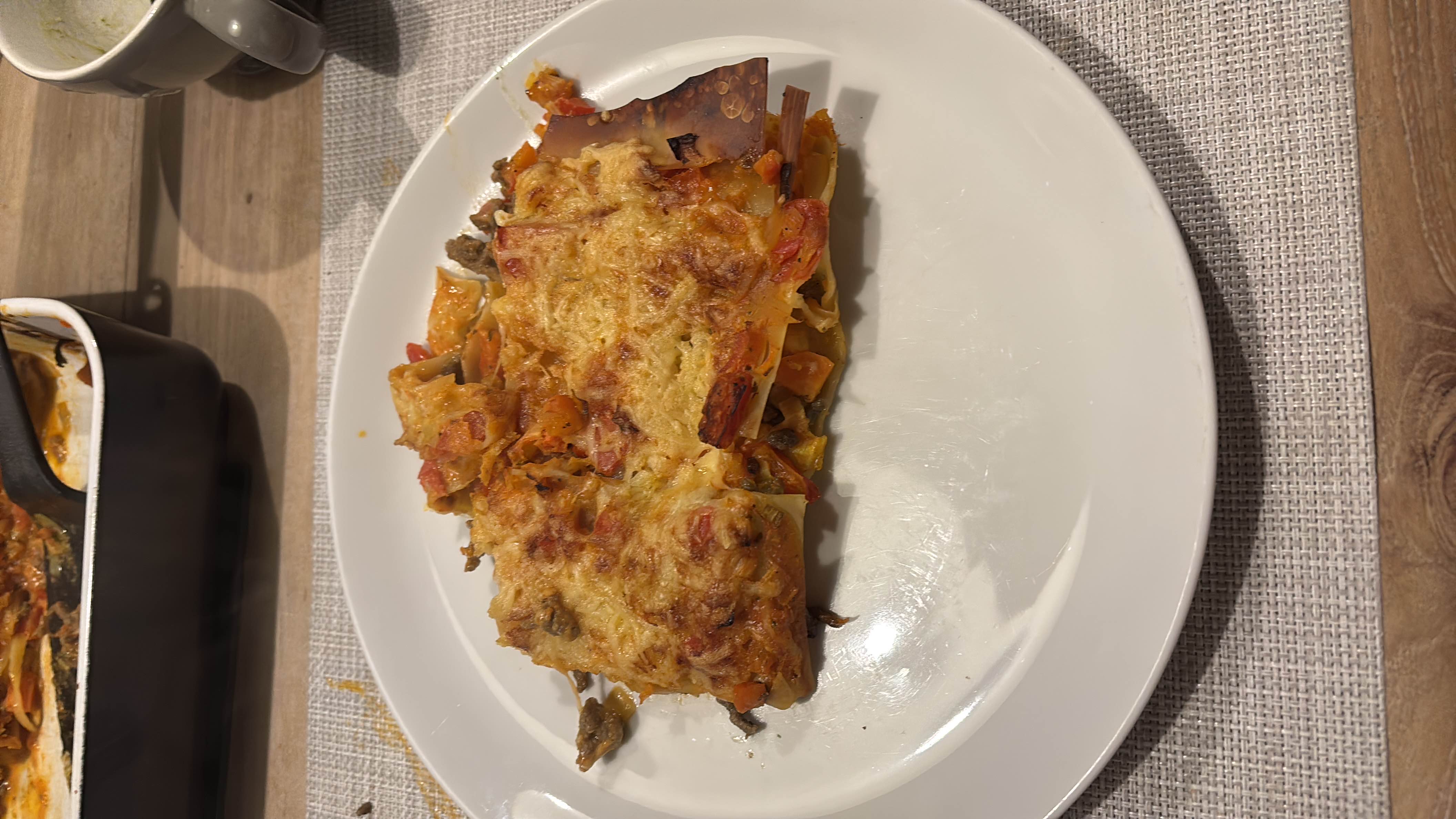 A serving of vegetable lasagna with pasta sheets, cheese, tomato sauce, and mixed vegetables, baked to perfection.