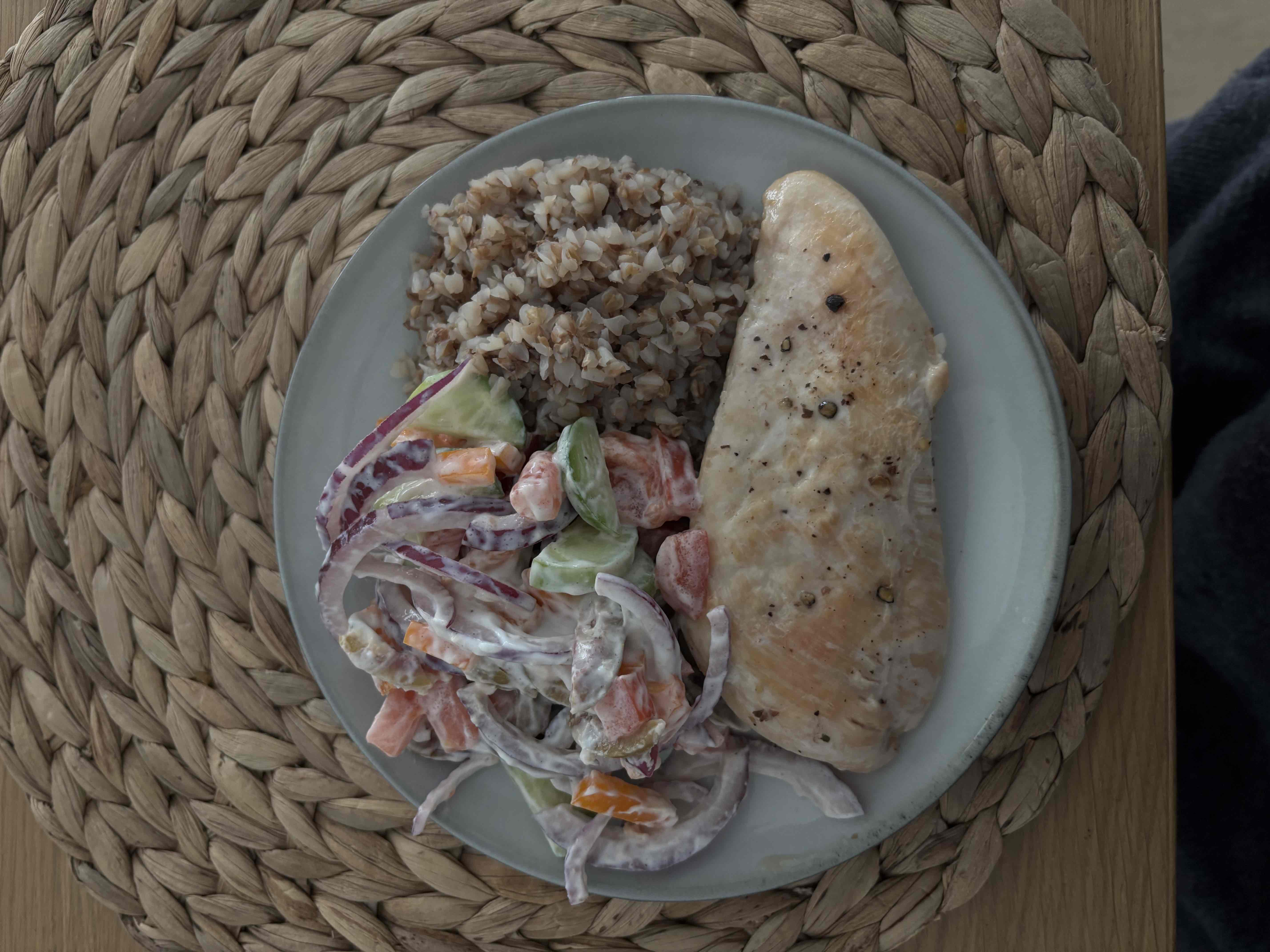 A balanced meal consisting of grilled chicken breast, buckwheat, and a vegetable salad with dressing.