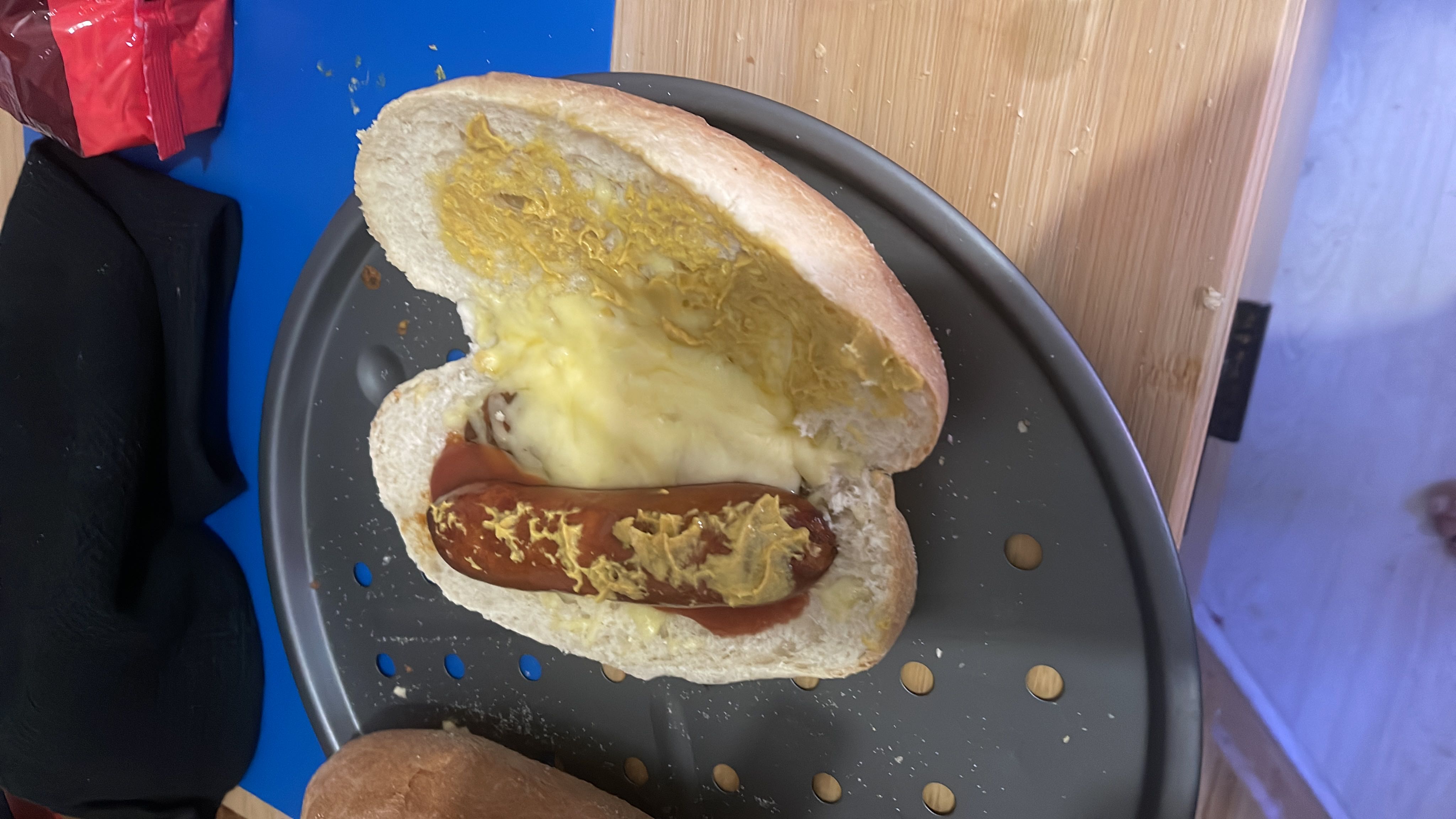 A hot dog with sausage, cheese, and condiments on a bread bun.