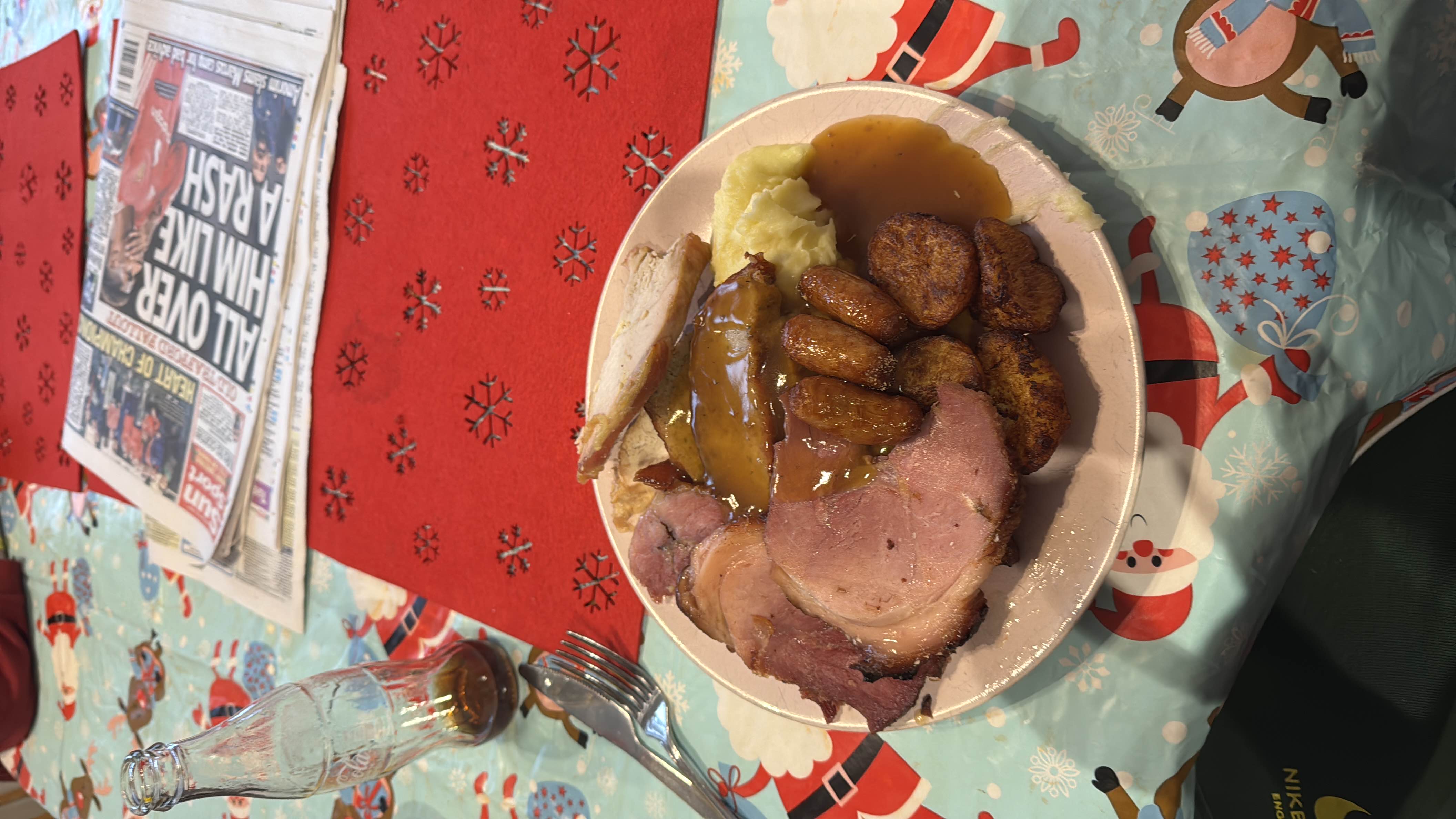 A hearty plate of ham, turkey, roast potatoes, gravy, and mashed potatoes.