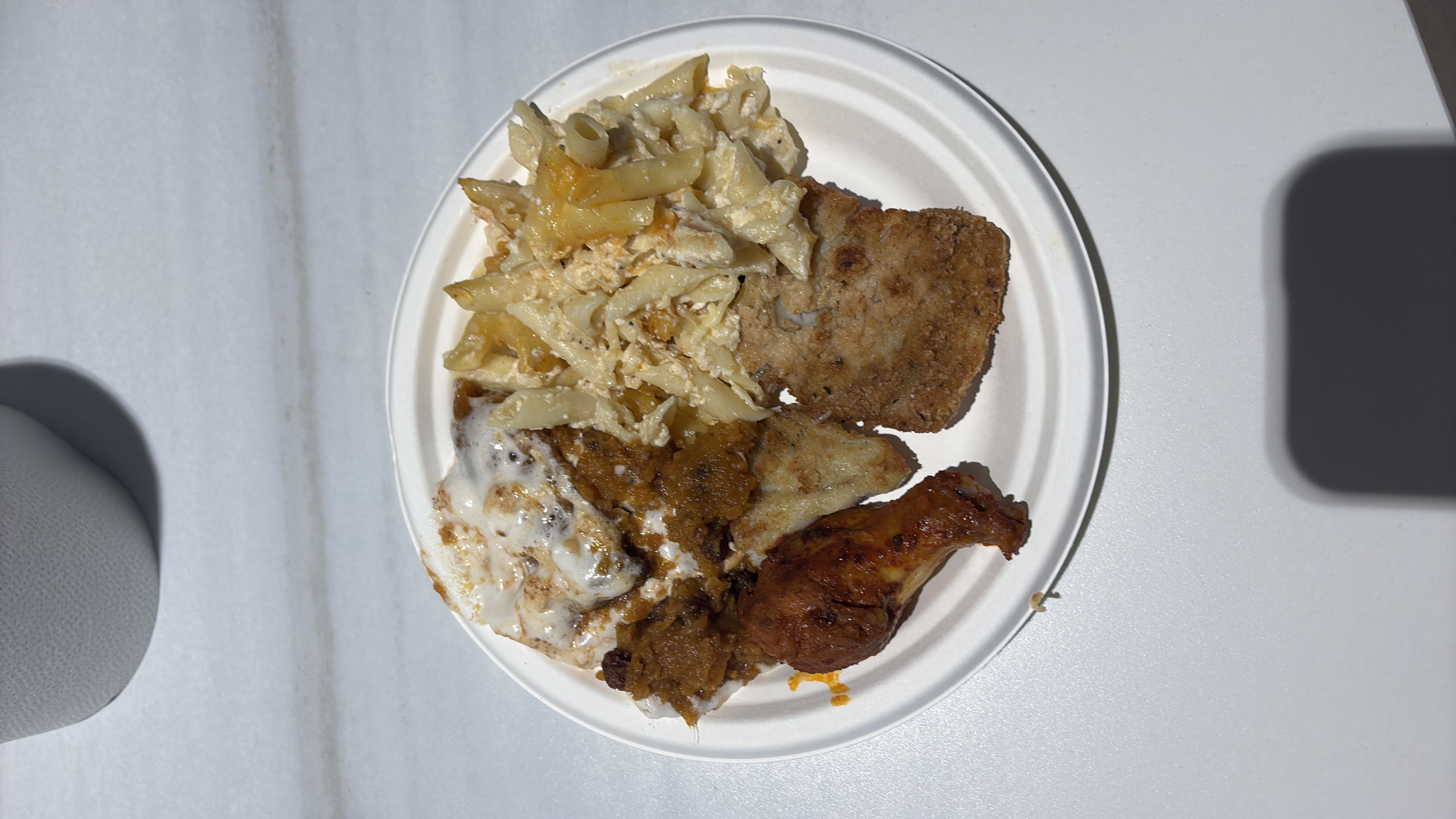 A plate featuring fried chicken, creamy pasta, and a breaded cutlet.