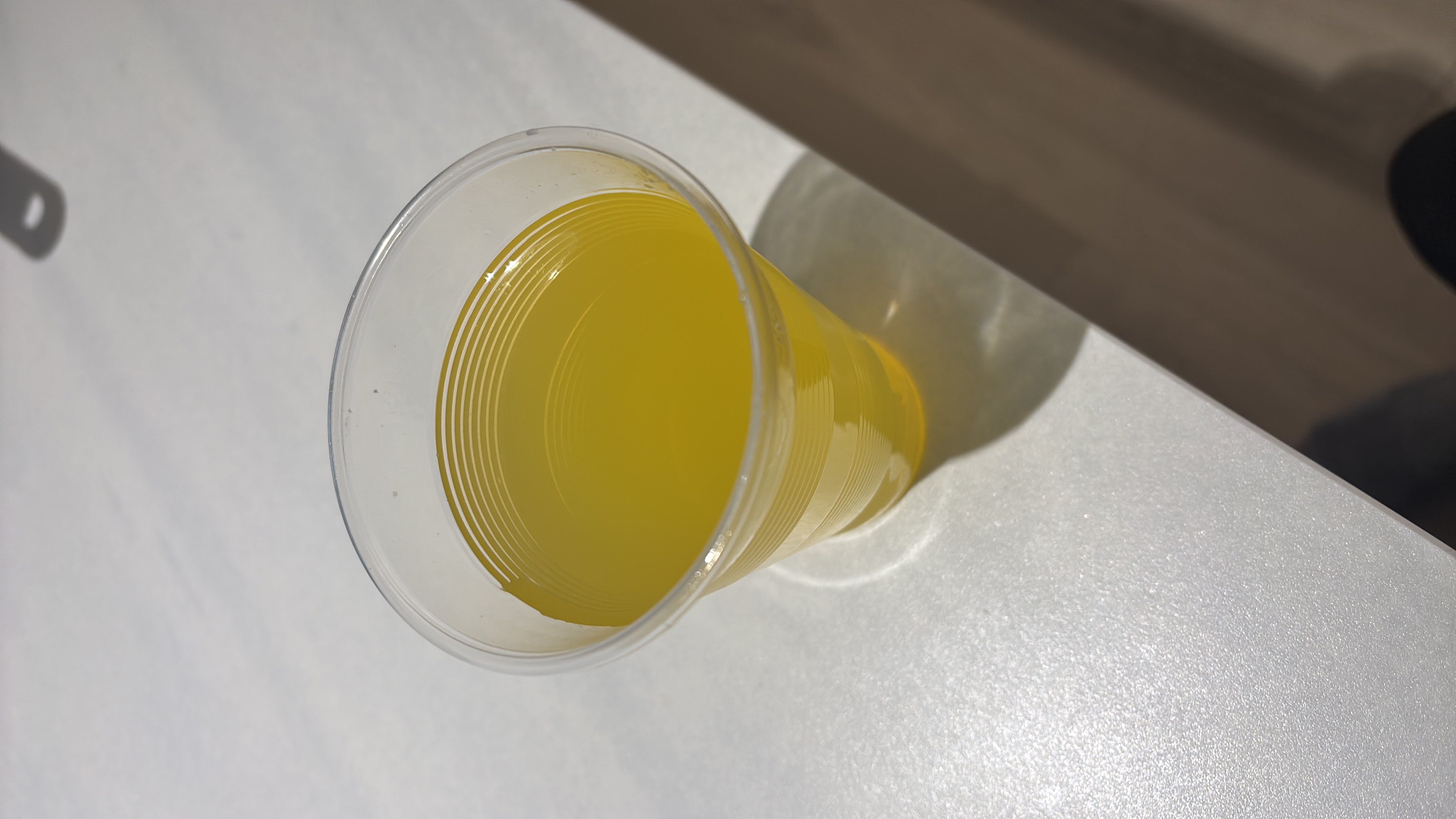 A sweet, yellow-colored beverage that appears to be lemon-flavored and served in a plastic cup.