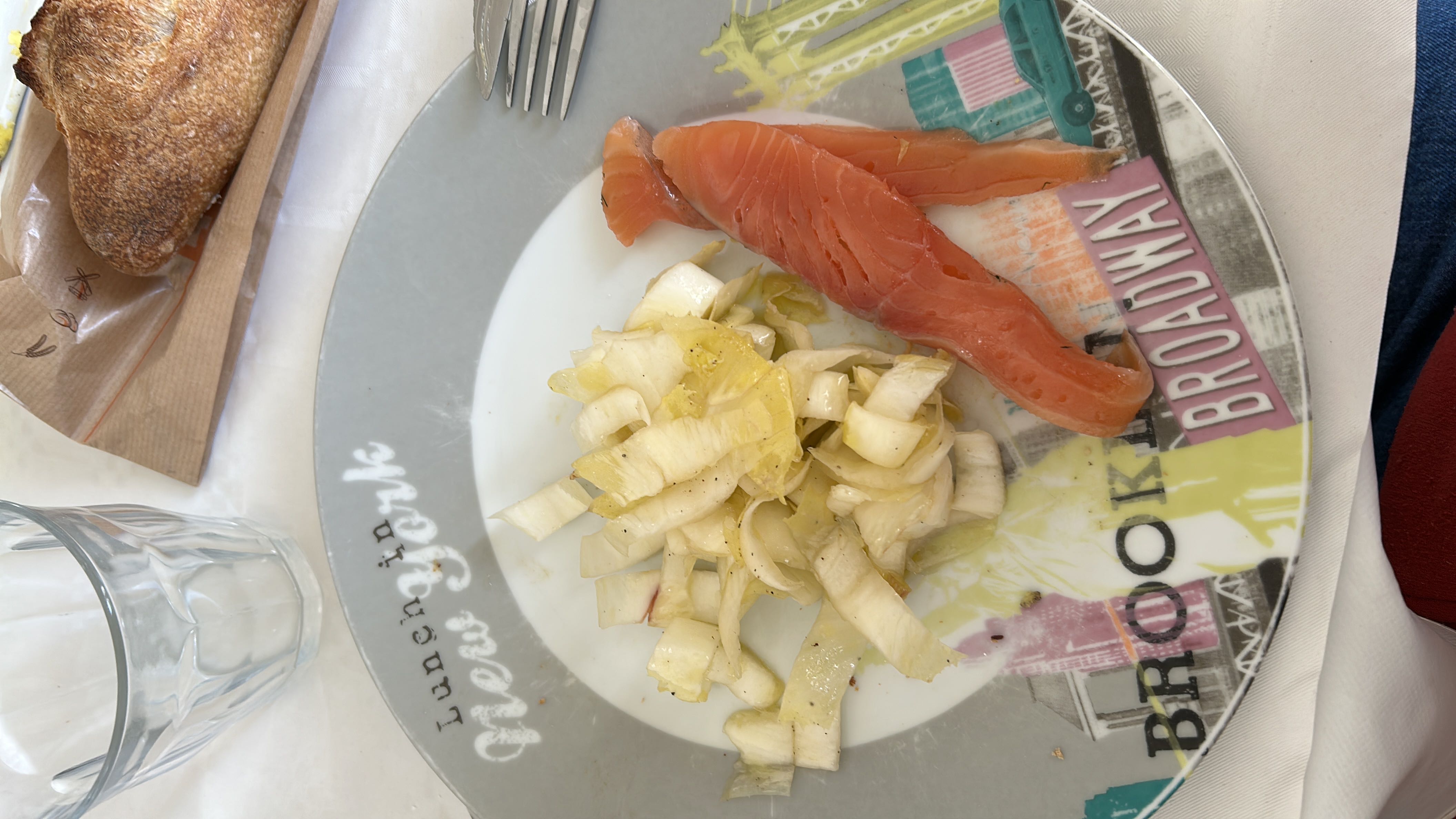 A light meal with smoked salmon slices, an endive salad, and a piece of bread.