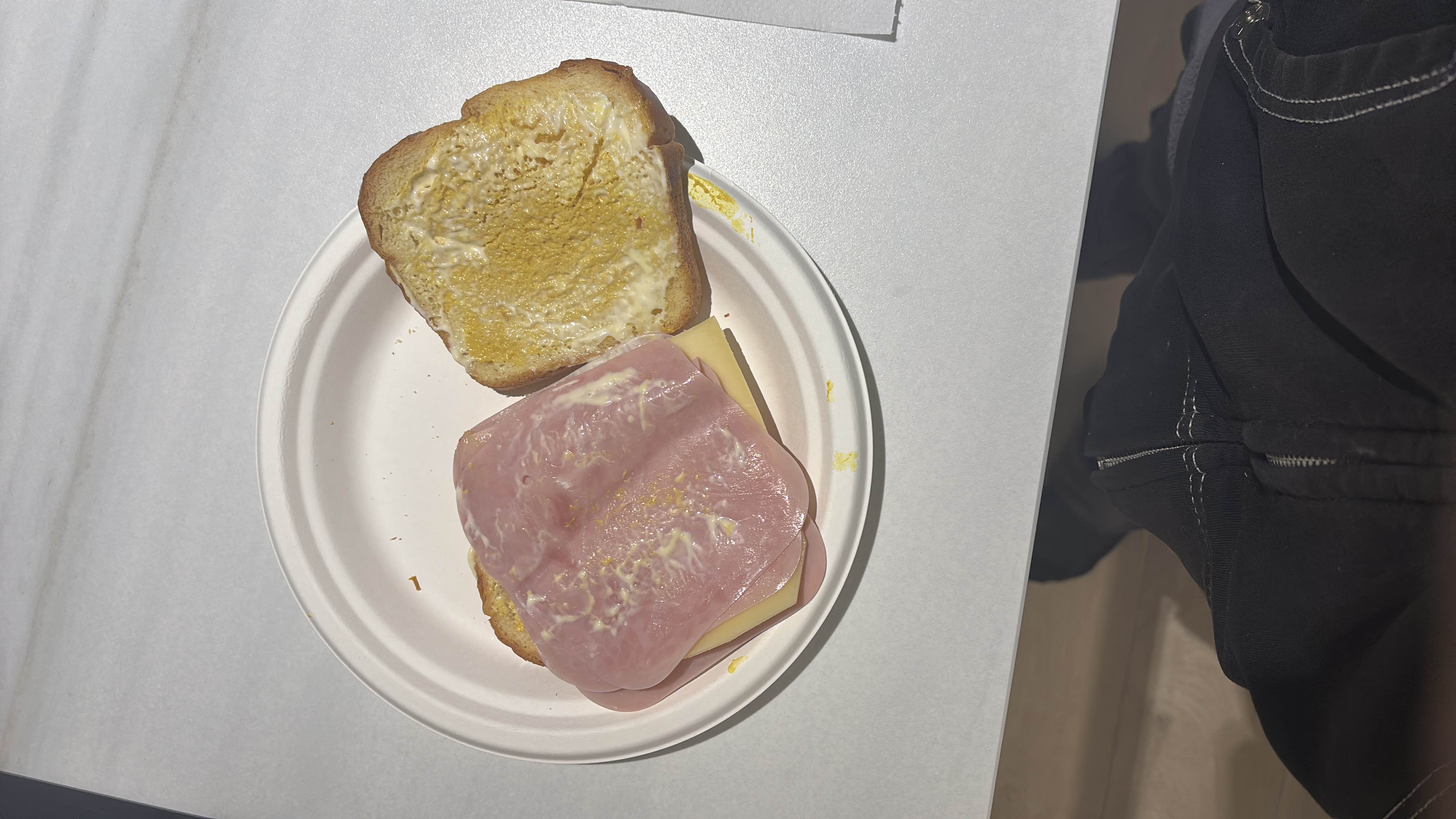 A simple ham and cheese sandwich with a light spread of condiments.
