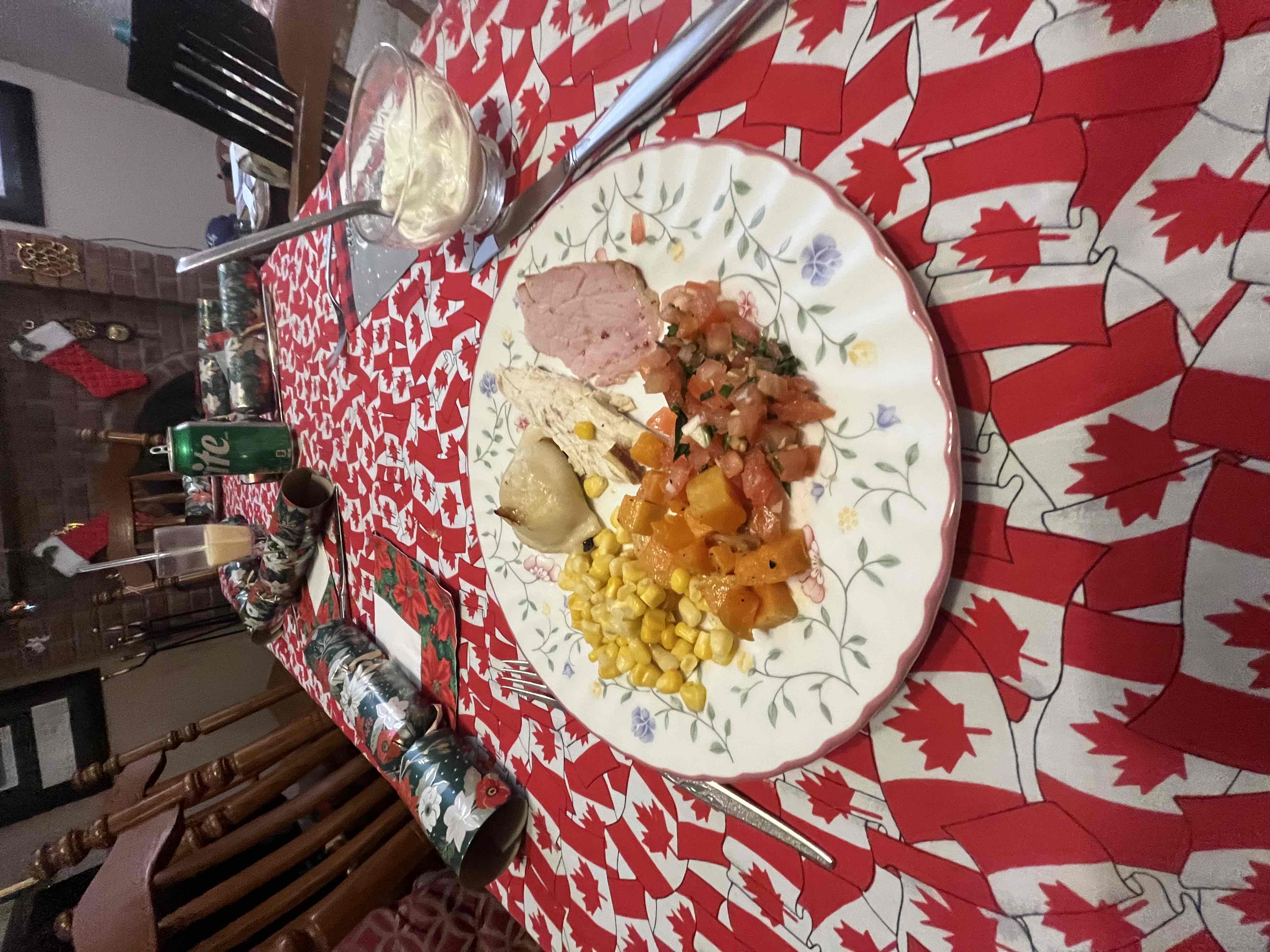 A holiday plate featuring turkey, ham, corn, roasted vegetables, and a perogy.