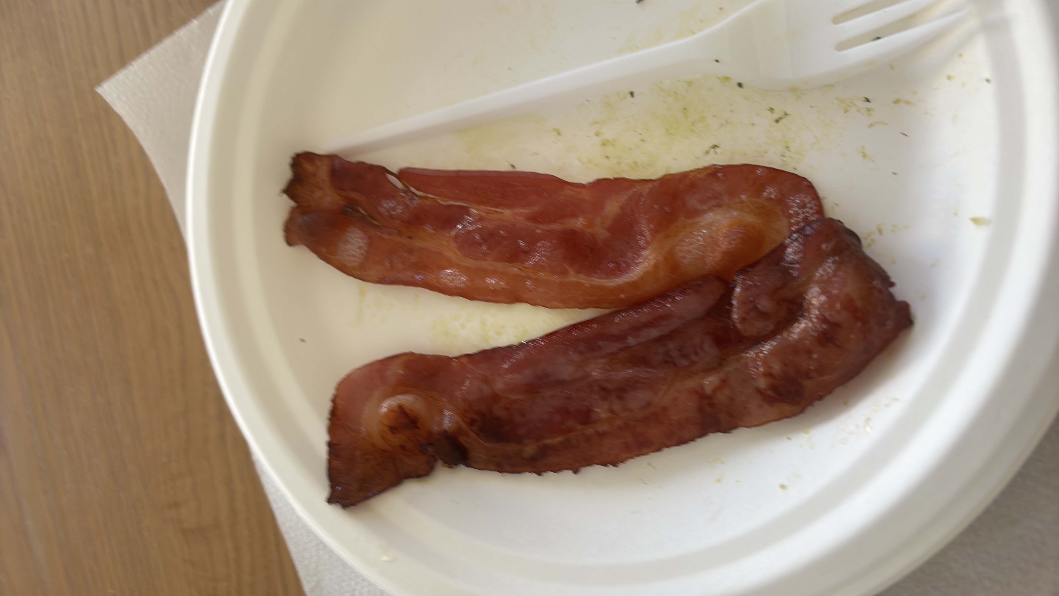 Cooked bacon slices that are relatively high in fat and moderate in protein.