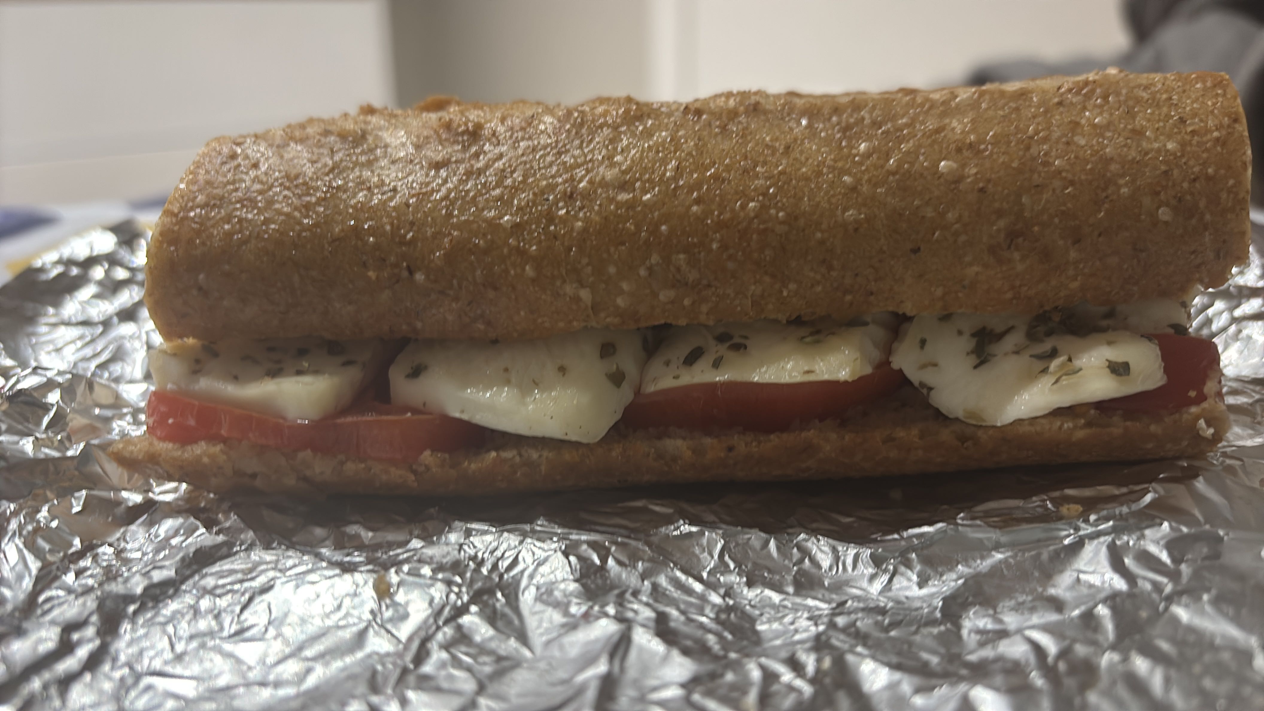 A wholesome sandwich with fresh tomatoes, mozzarella, and herbs on whole wheat bread.