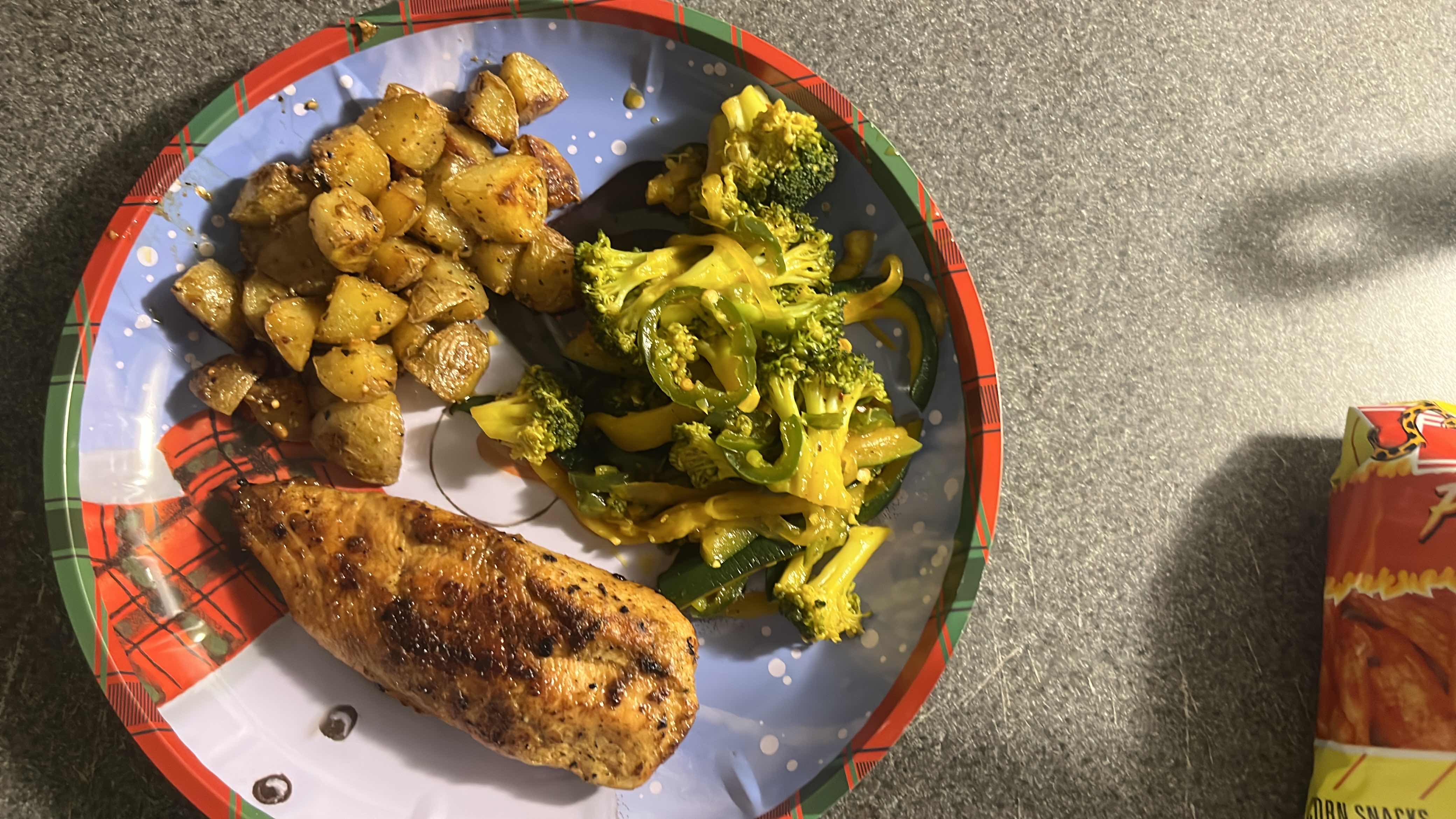 A plate featuring roasted chicken breast, seasoned potatoes, and mixed vegetables.