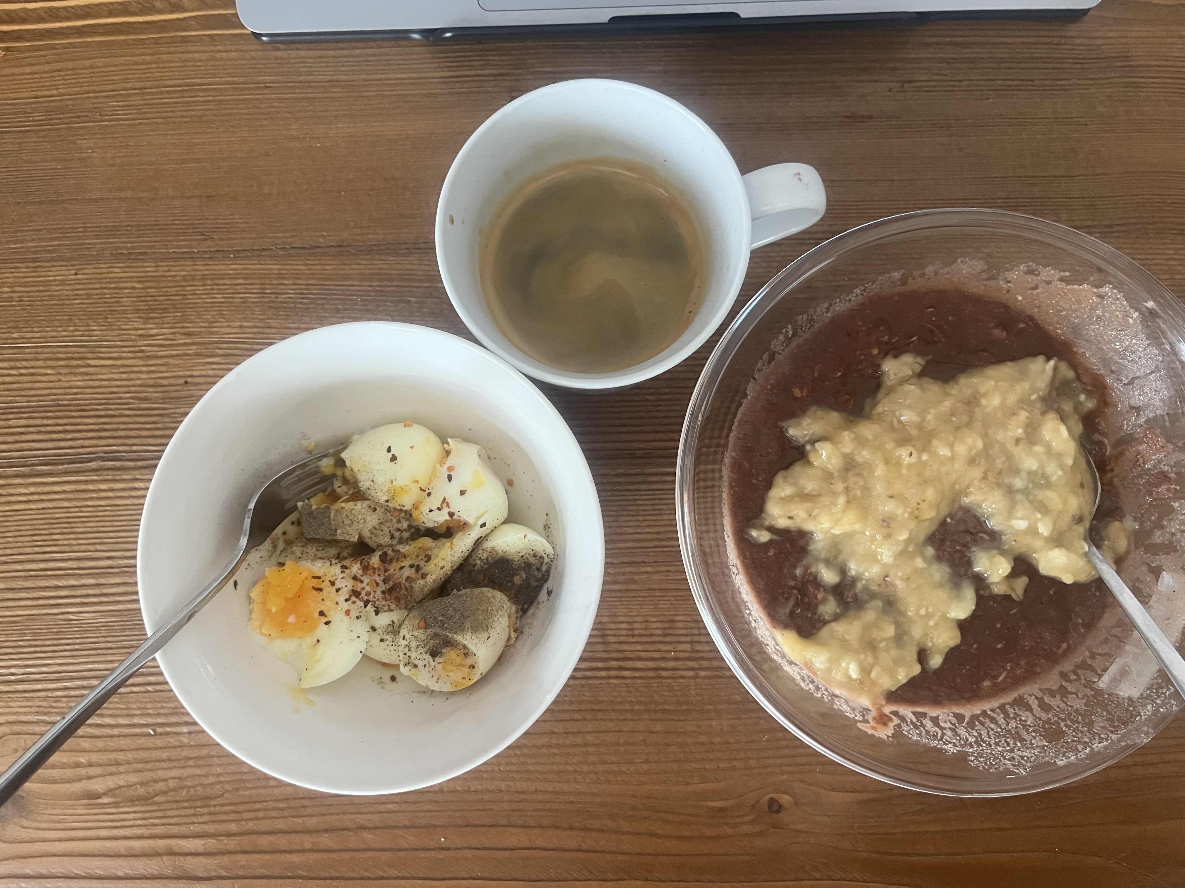 A balanced meal consisting of boiled eggs, banana, chocolate oatmeal, and black coffee, providing a good mix of protein, carbs, and fats.