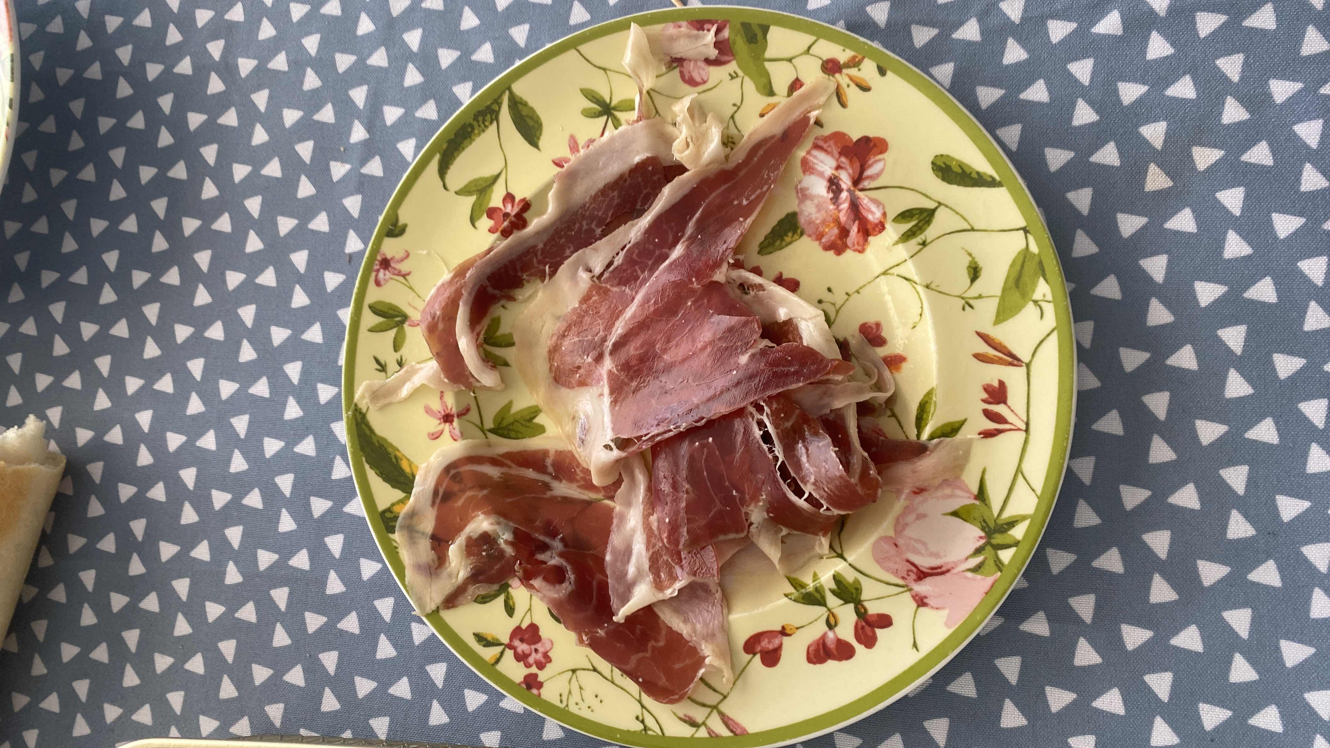 A plate of thinly sliced cured ham, high in protein and fats, with no carbohydrates.