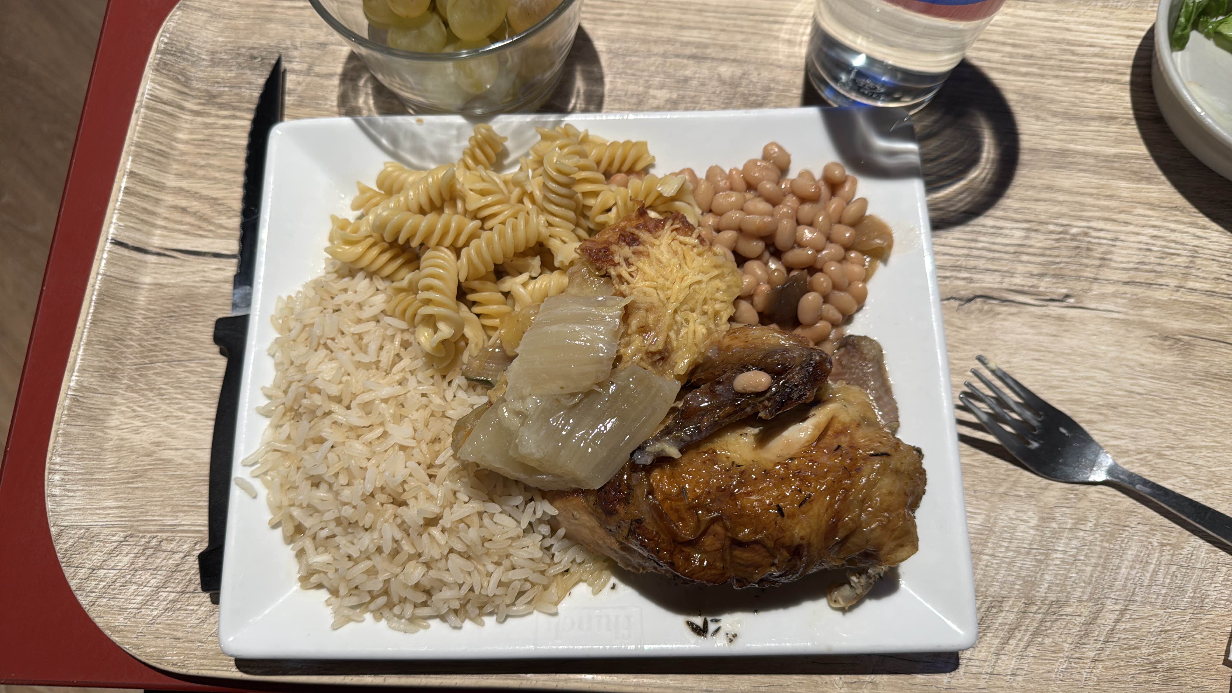 A balanced meal consisting of grilled chicken, rice, pasta, beans, and onions, providing a mix of protein, carbohydrates, and fats.