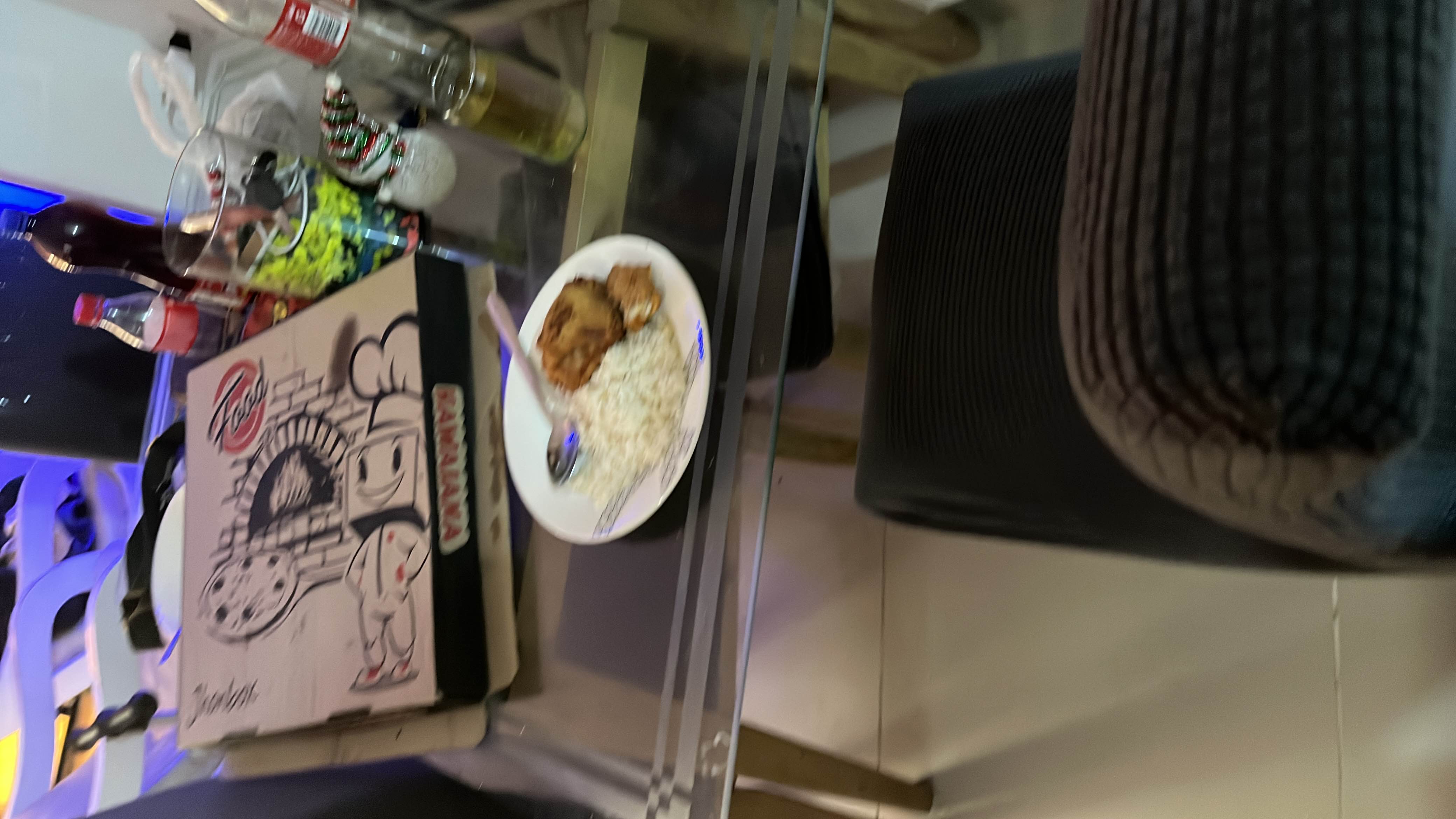 The image shows a meal consisting of rice, chicken, and pizza, along with beverages on a table.