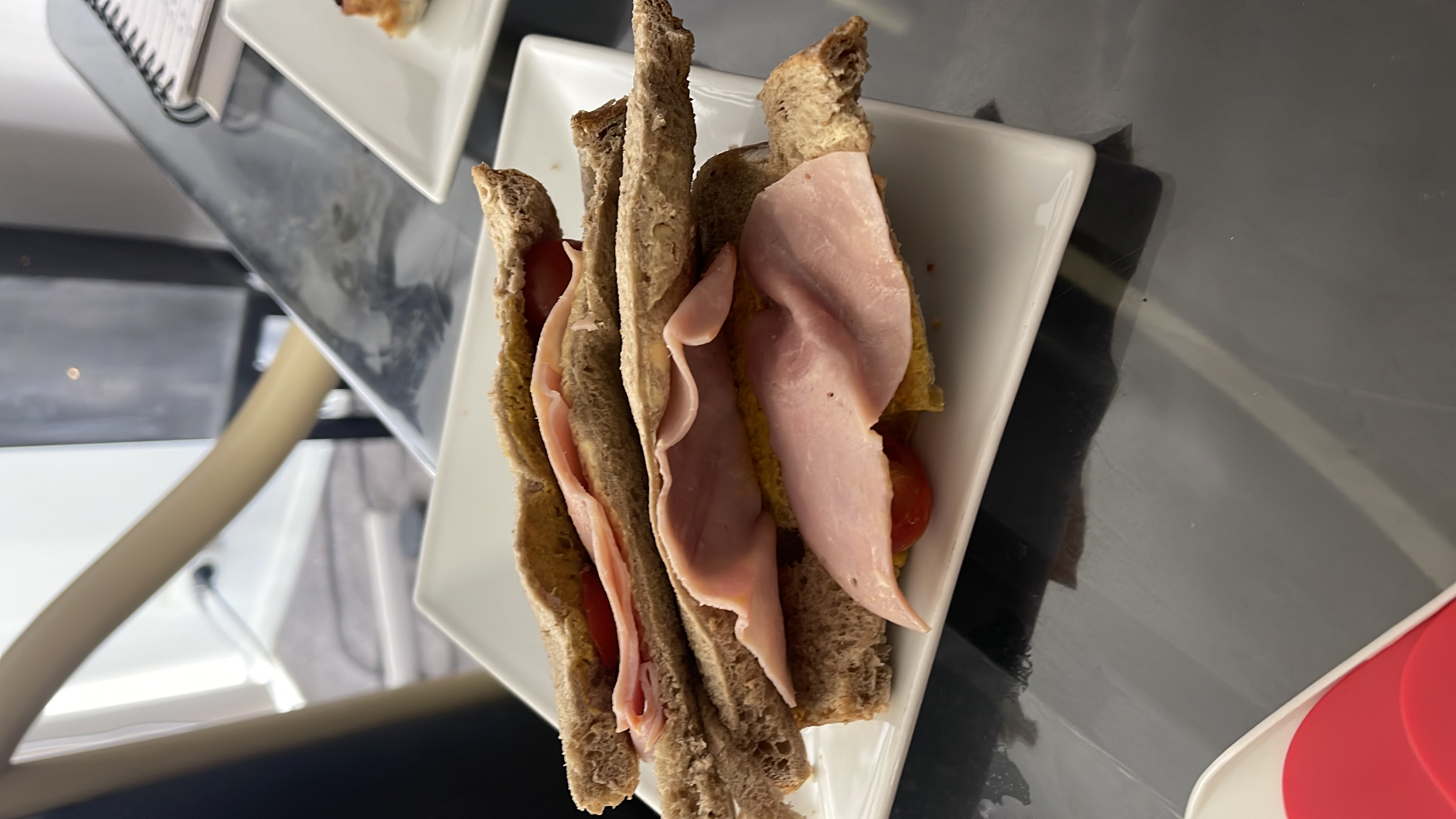 A sandwich made with whole grain bread, ham, tomato, mustard, and egg, providing a balanced mix of protein, carbs, and fats.