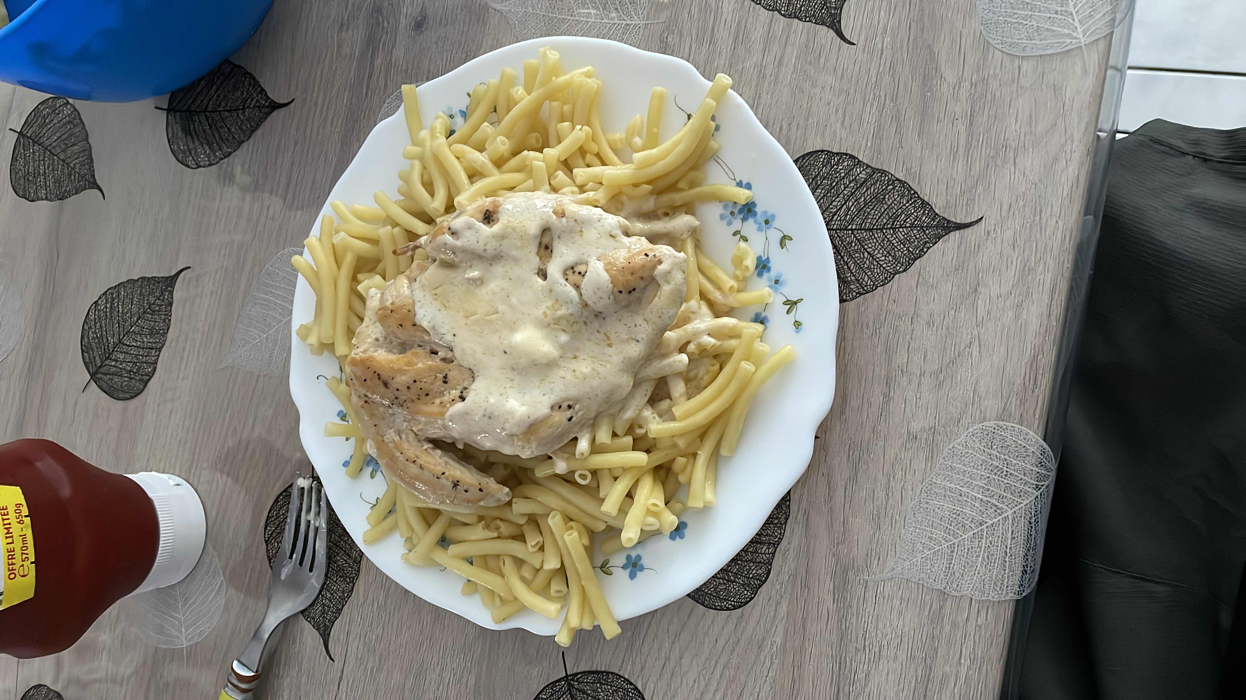 A plate of pasta topped with chicken breast and creamy sauce, providing a balanced mix of protein, carbs, and fats.